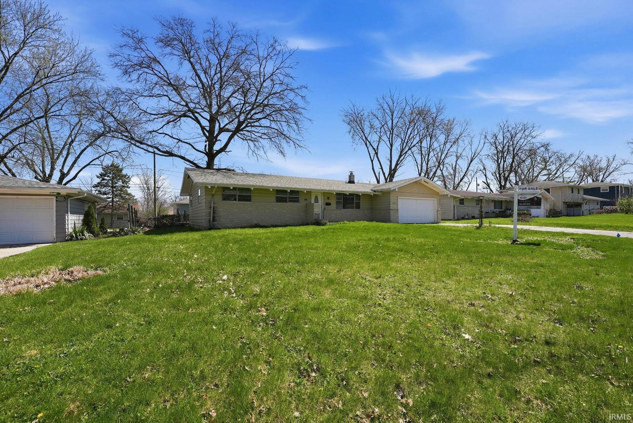 Ranch-style residence featuring a brick facade, attached single-car garage, and a large front lawn