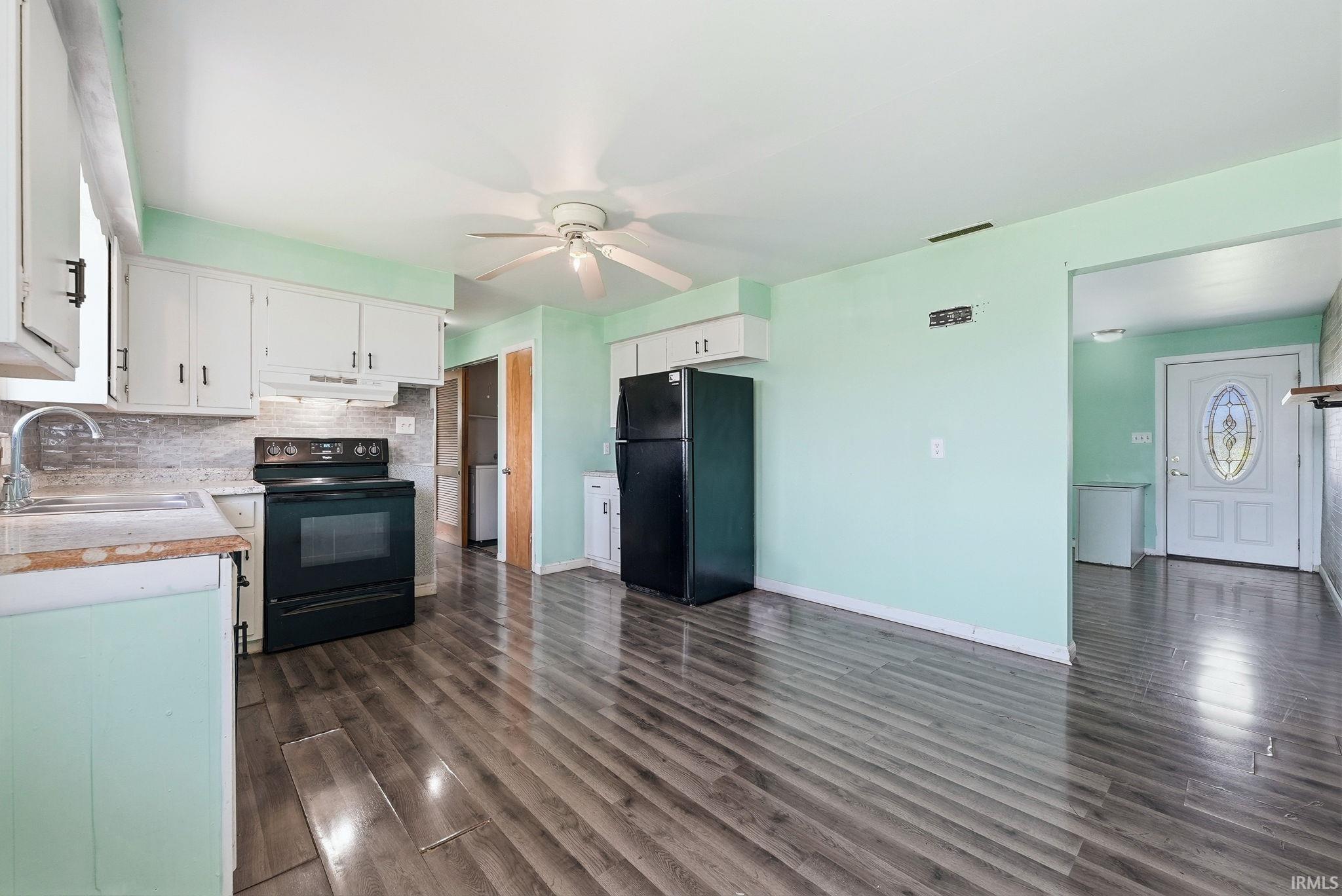 Kitchen featuring wood-finish flooring, white cabinetry, black appliances, and a ceiling fan