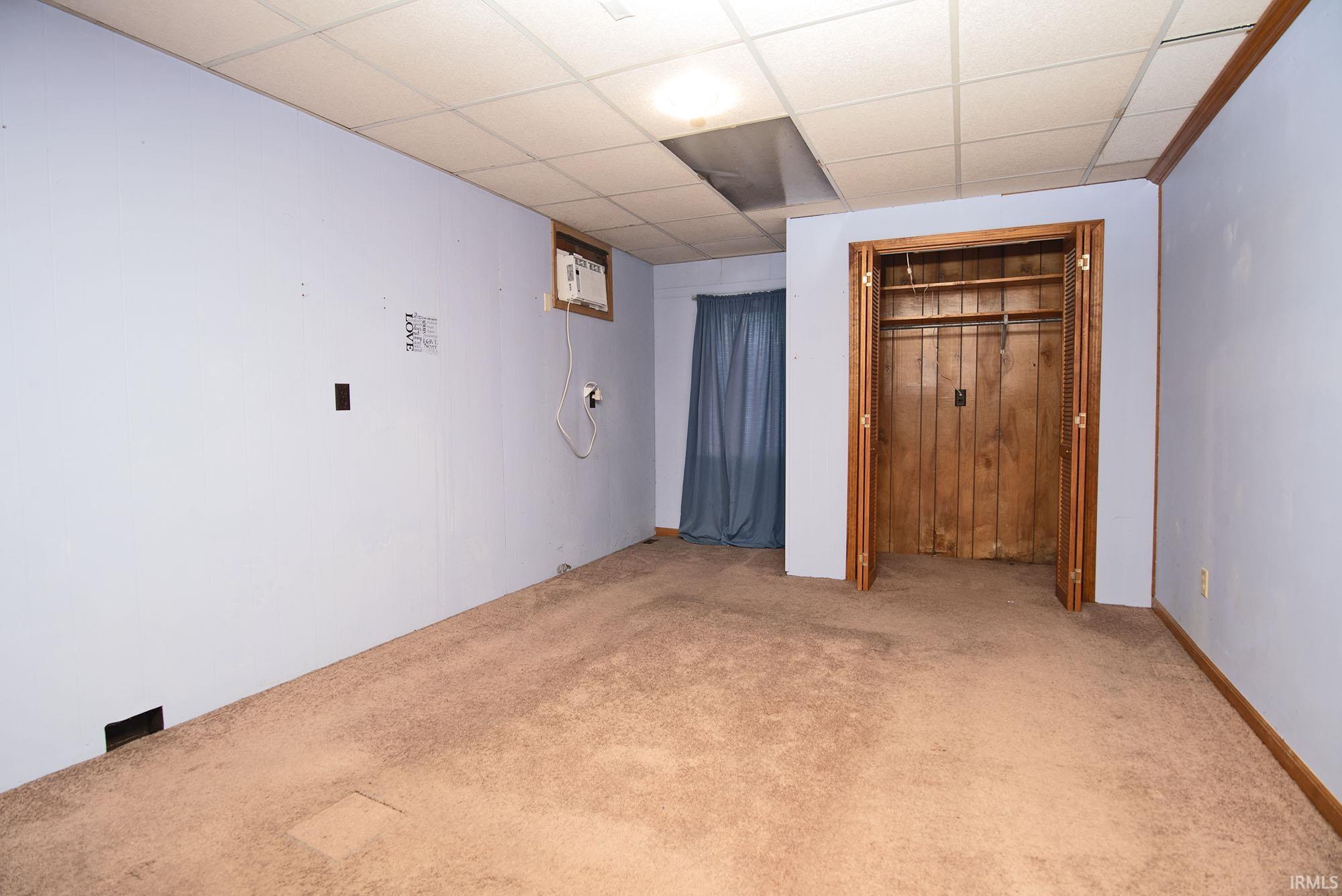Carpeted interior space featuring a drop ceiling and light blue walls