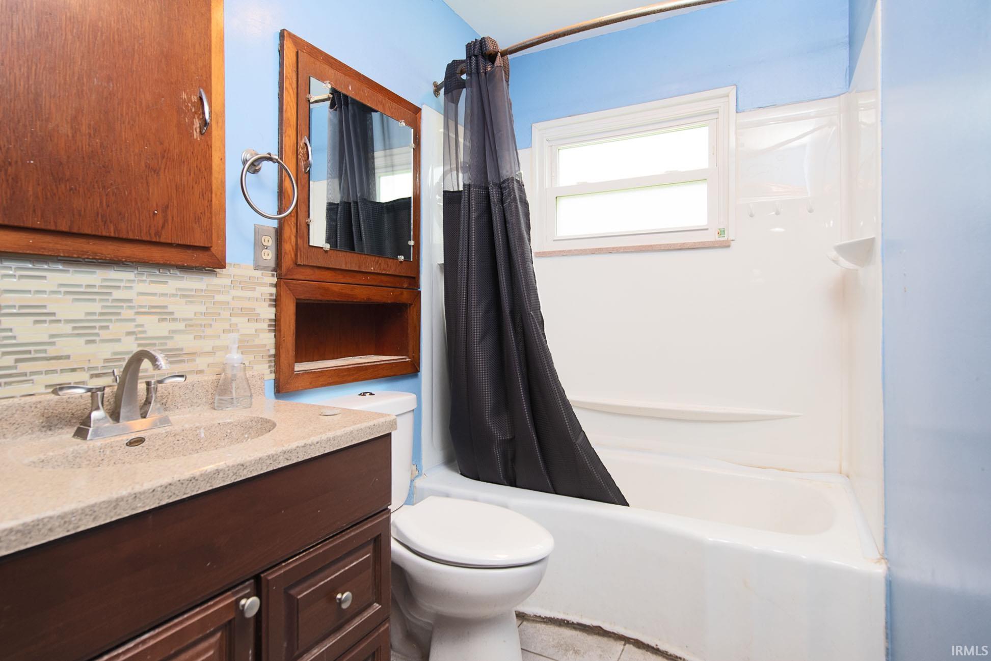 Bathroom featuring a full vanity with an integrated sink, mosaic tile backsplash, and a medicine cabinet