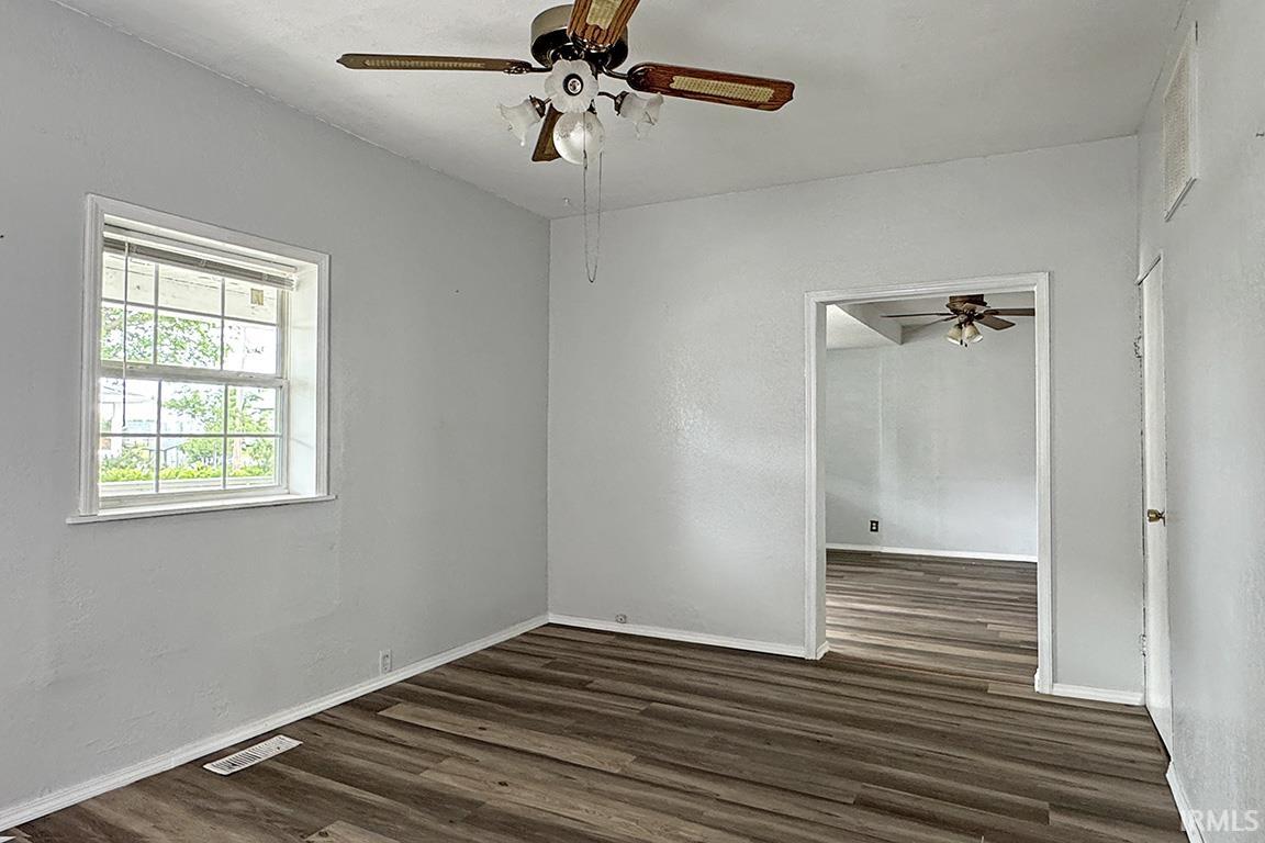 Interior space featuring wood-finish flooring, light gray wall finishes, a ceiling fan with integrated lighting, and a white-framed window