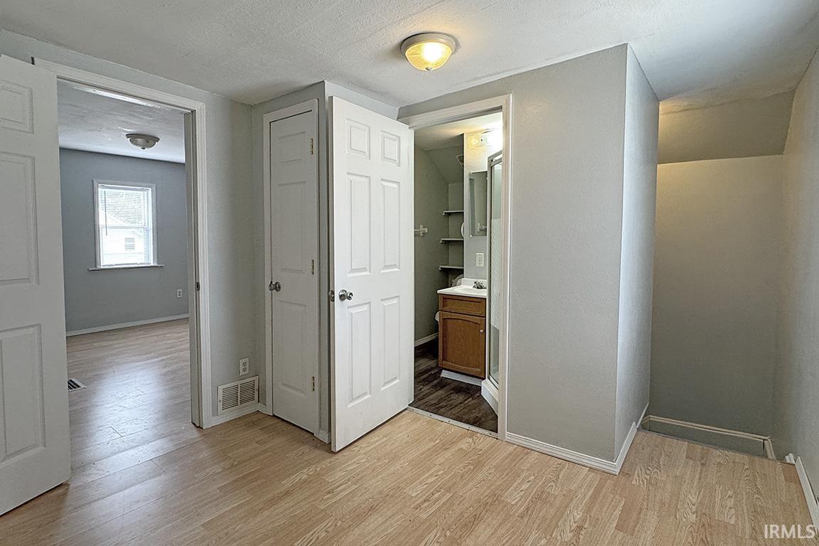 Interior room featuring wood-finish flooring, light gray wall paint, and white trim