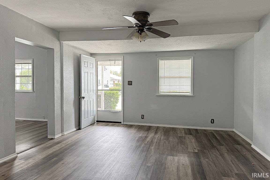 Spacious interior featuring wood-finish flooring, light grey painted walls, white trim, and a ceiling fan