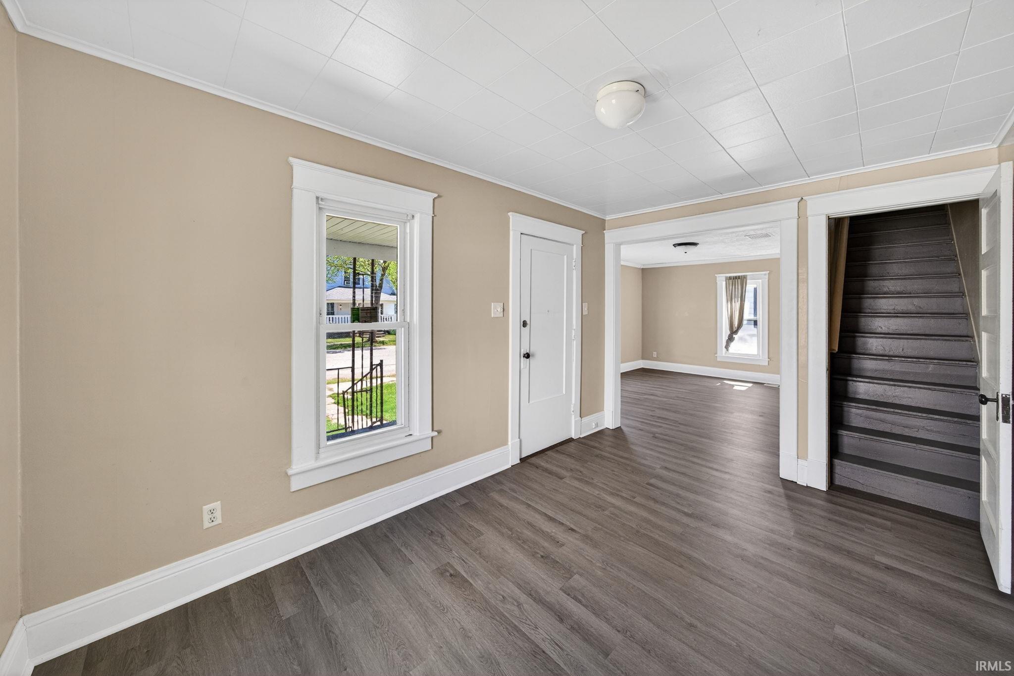 Spacious room with wood-finish flooring, neutral-toned walls, and white trim