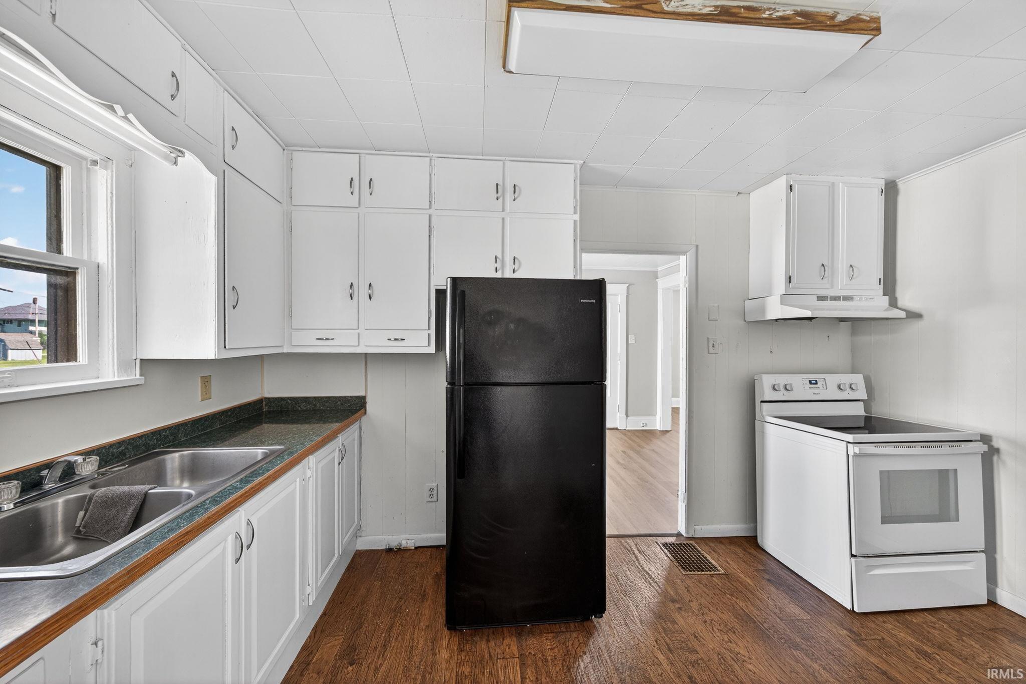 Kitchen featuring white cabinetry, dark countertop, and vinyl plank flooring
