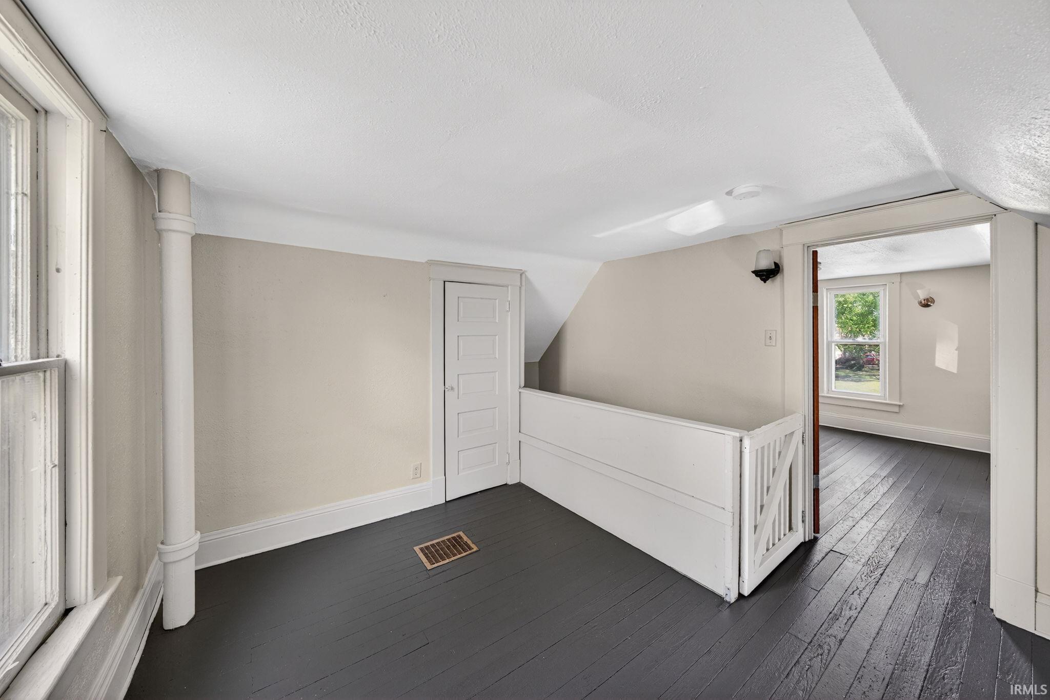 Loft featuring painted wood-finish flooring, light-toned wall paint, and white trim