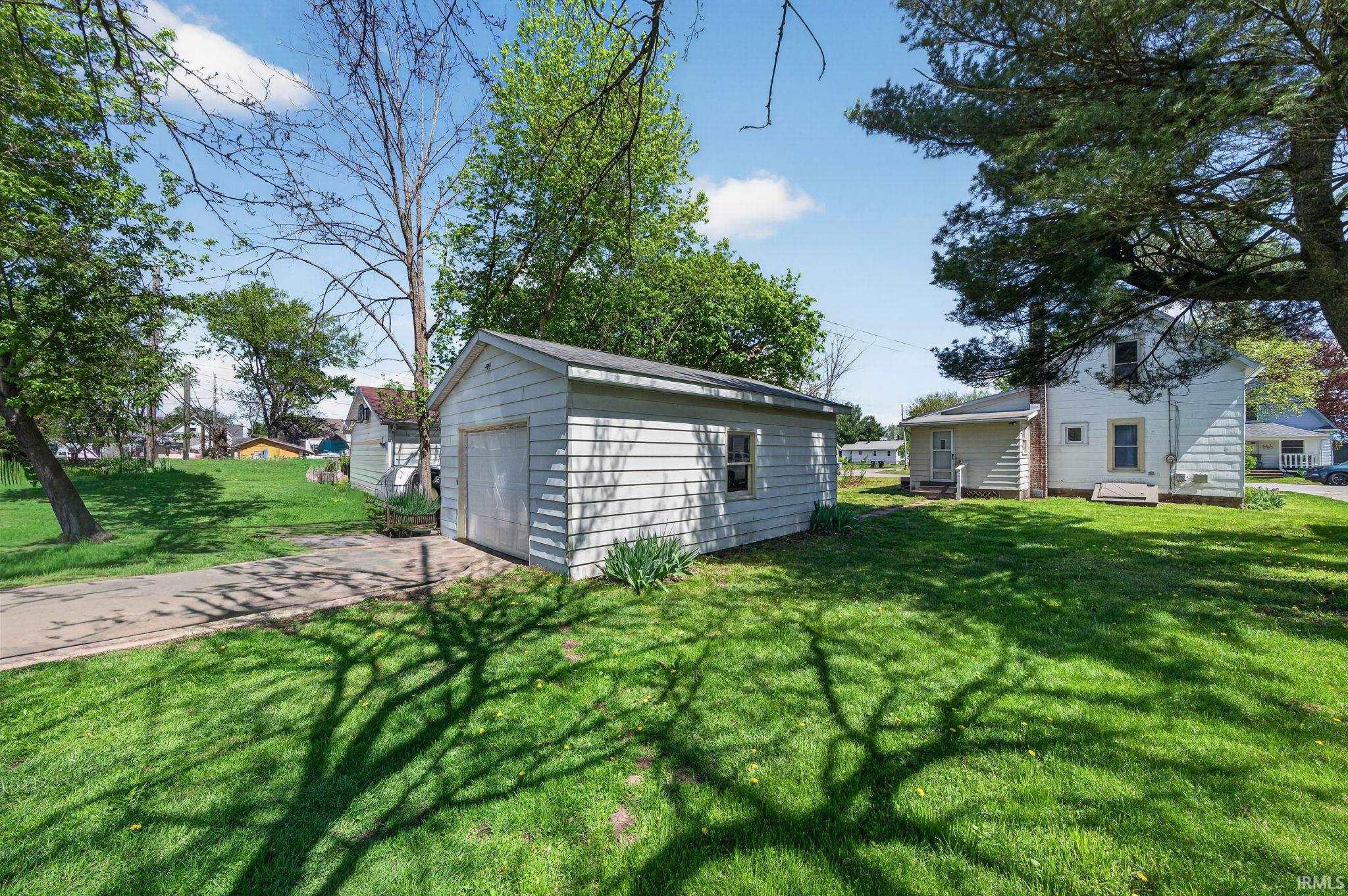 Detached white garage with horizontal siding, a single garage door, and a side window