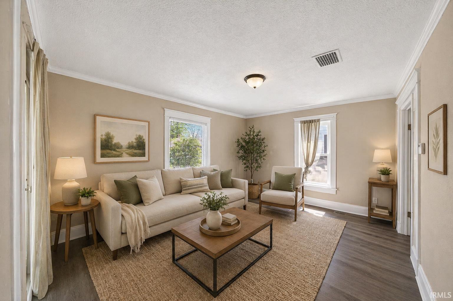 Living area featuring wood-finish flooring, two windows with white trim, and crown molding