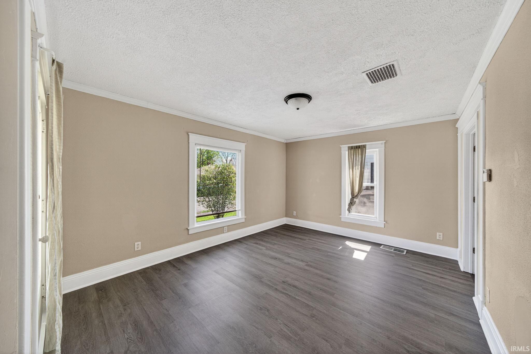 Spacious room featuring vinyl plank flooring, neutral-toned walls, and white trim
