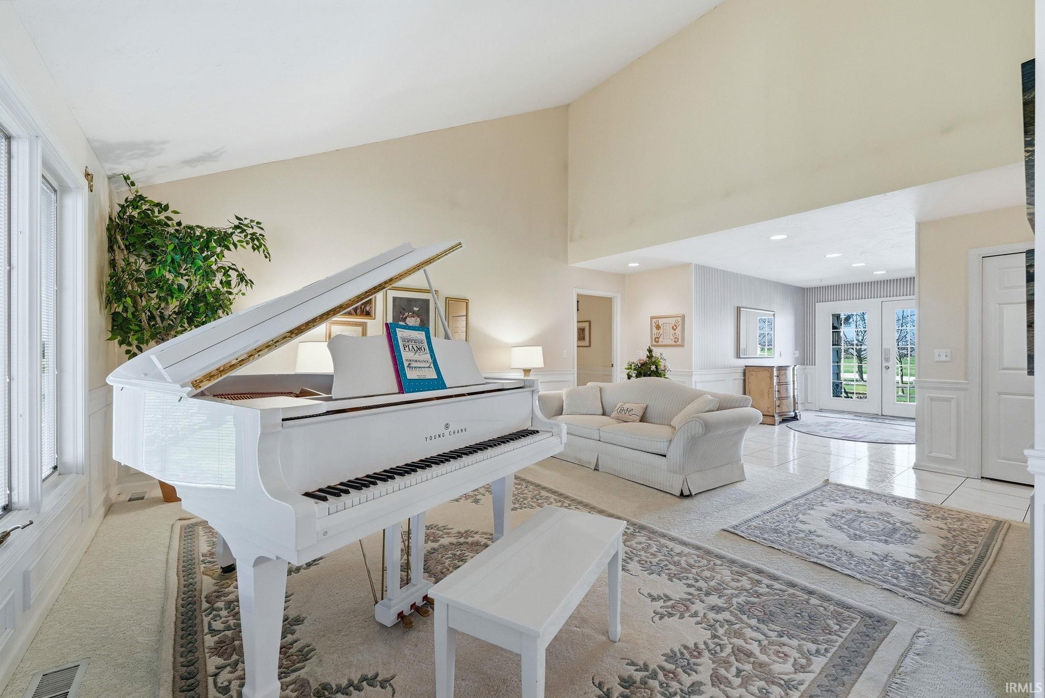 Living area with a high ceiling, french doors, recessed lighting, and wainscoting