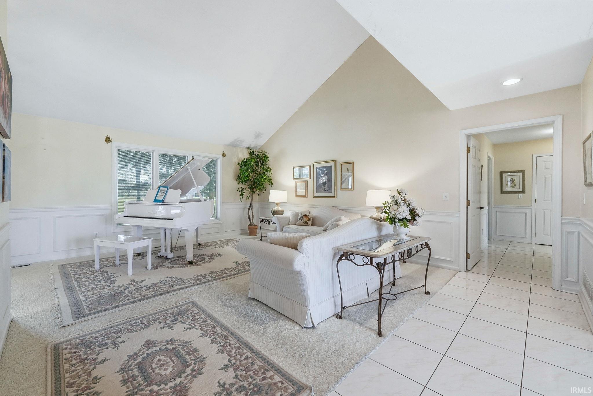 Living area featuring wainscoting, a decorative wall, and vaulted ceiling