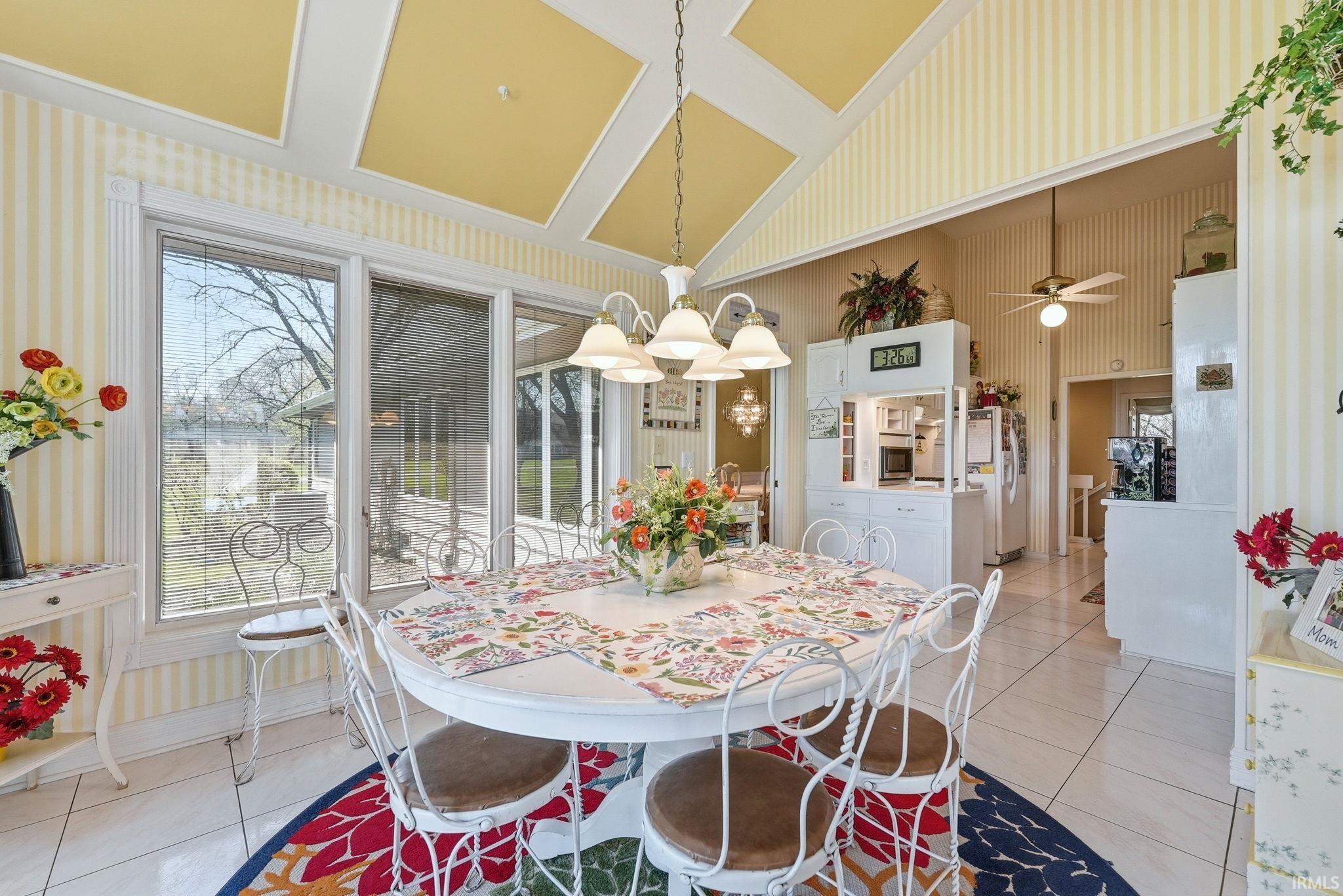 Dining space with light tile patterned floors, lofted ceiling, a ceiling fan, and suspended lighting