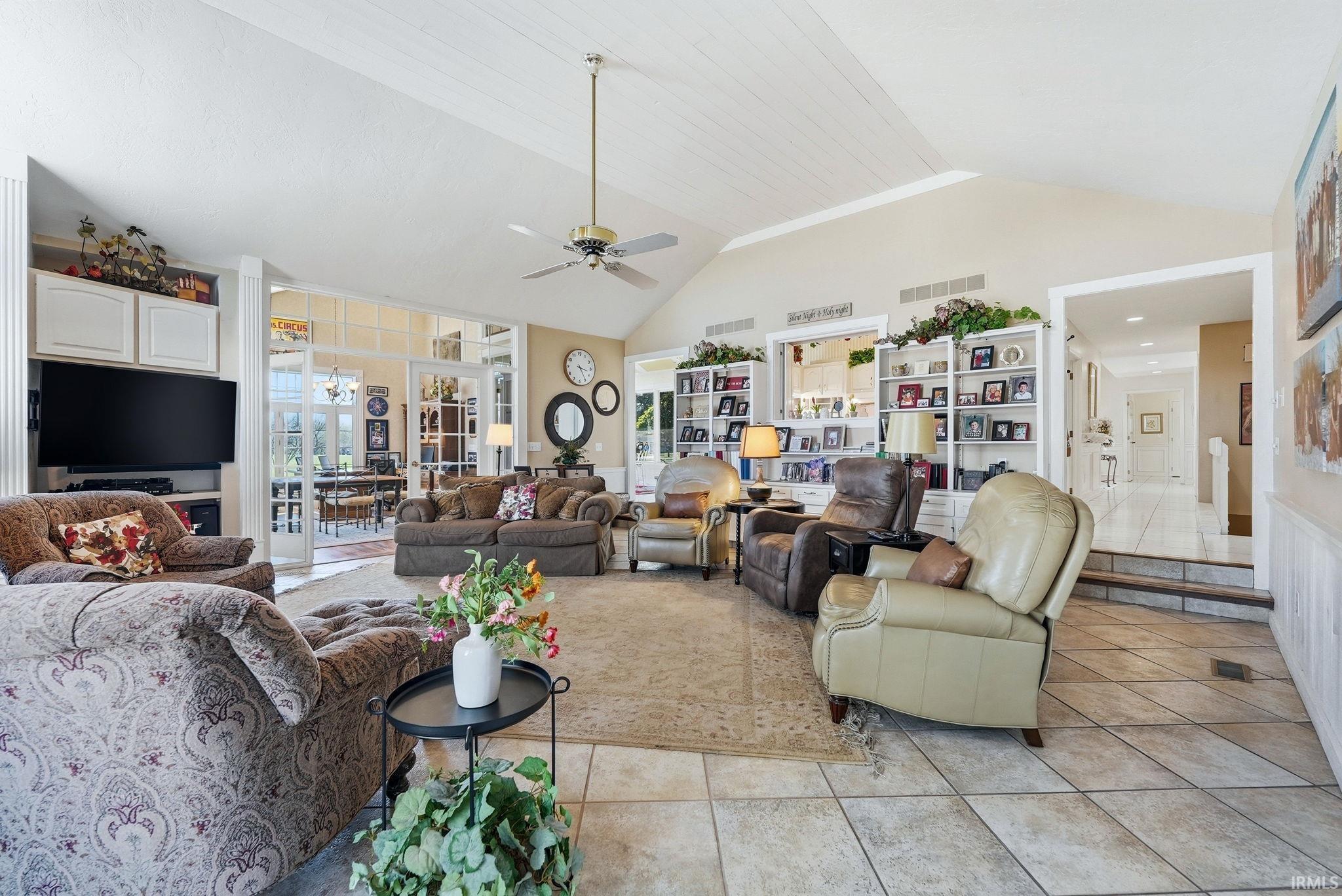Living area featuring a ceiling fan, light tile patterned floors, and a high ceiling