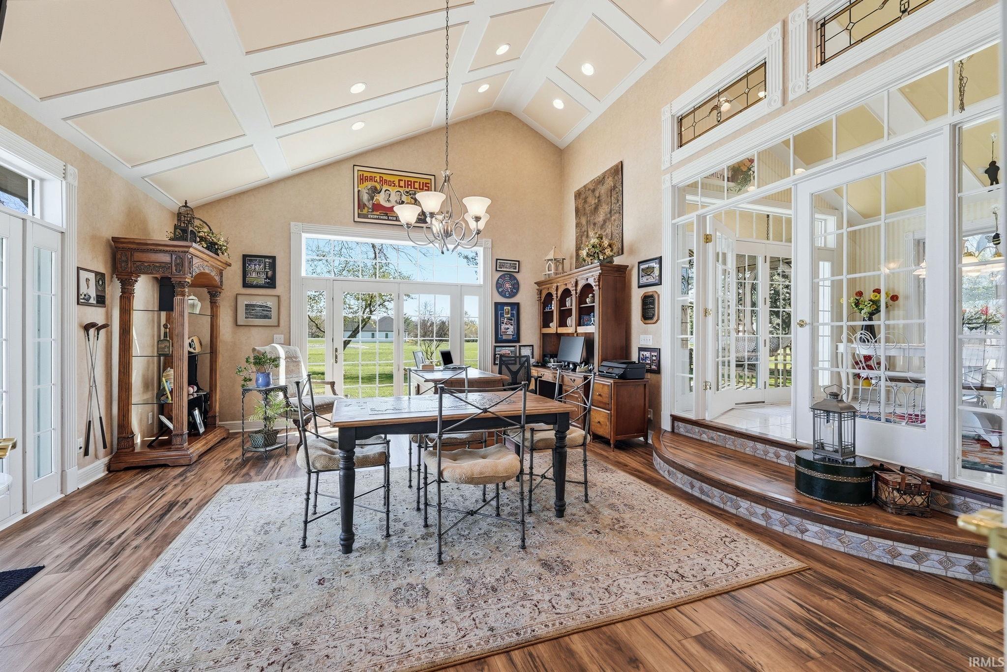 Dining room with vaulted ceiling, a chandelier, wood finished floors, and high coffered ceiling