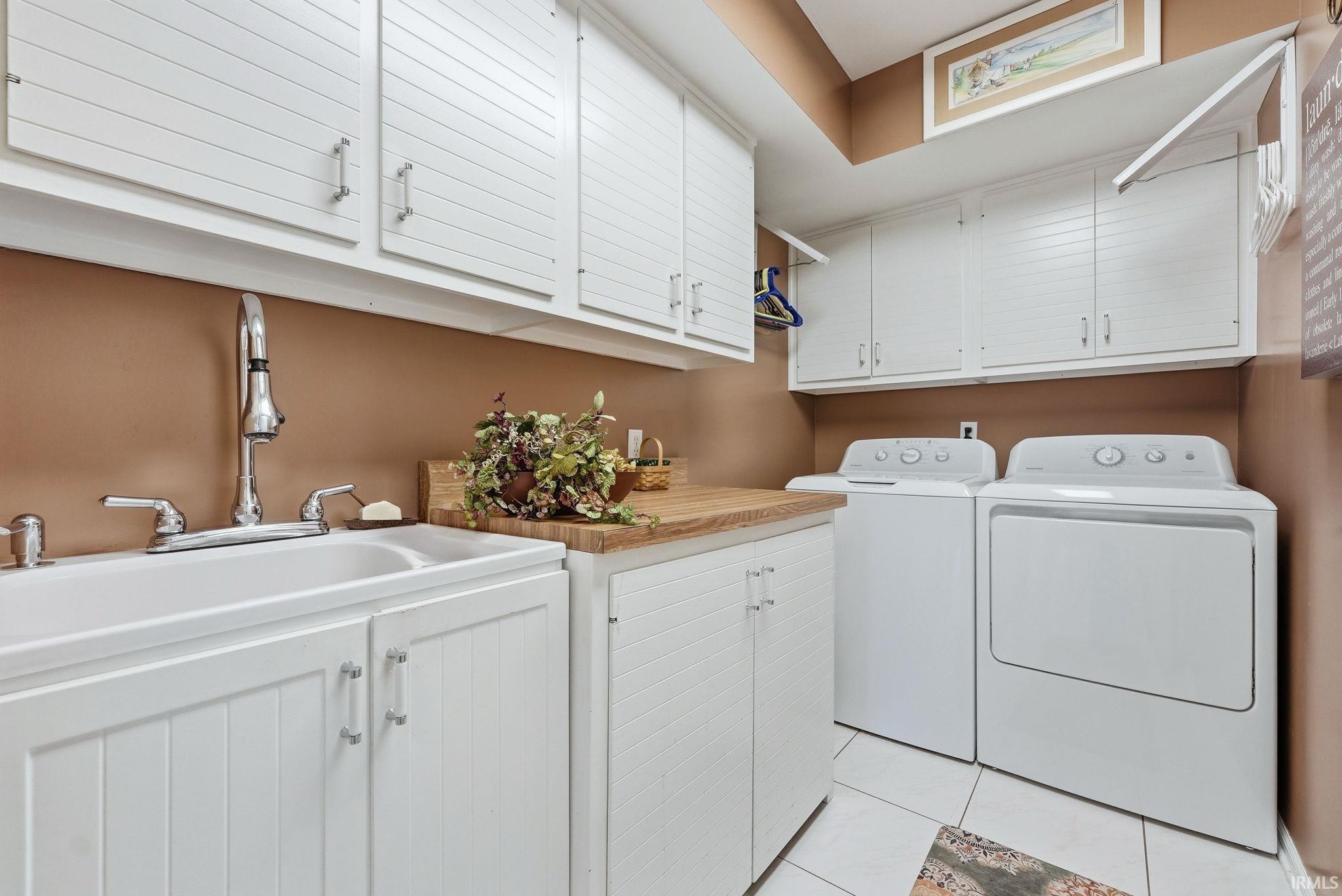 Laundry room featuring cabinet space, light tile patterned floors, and washer and clothes dryer