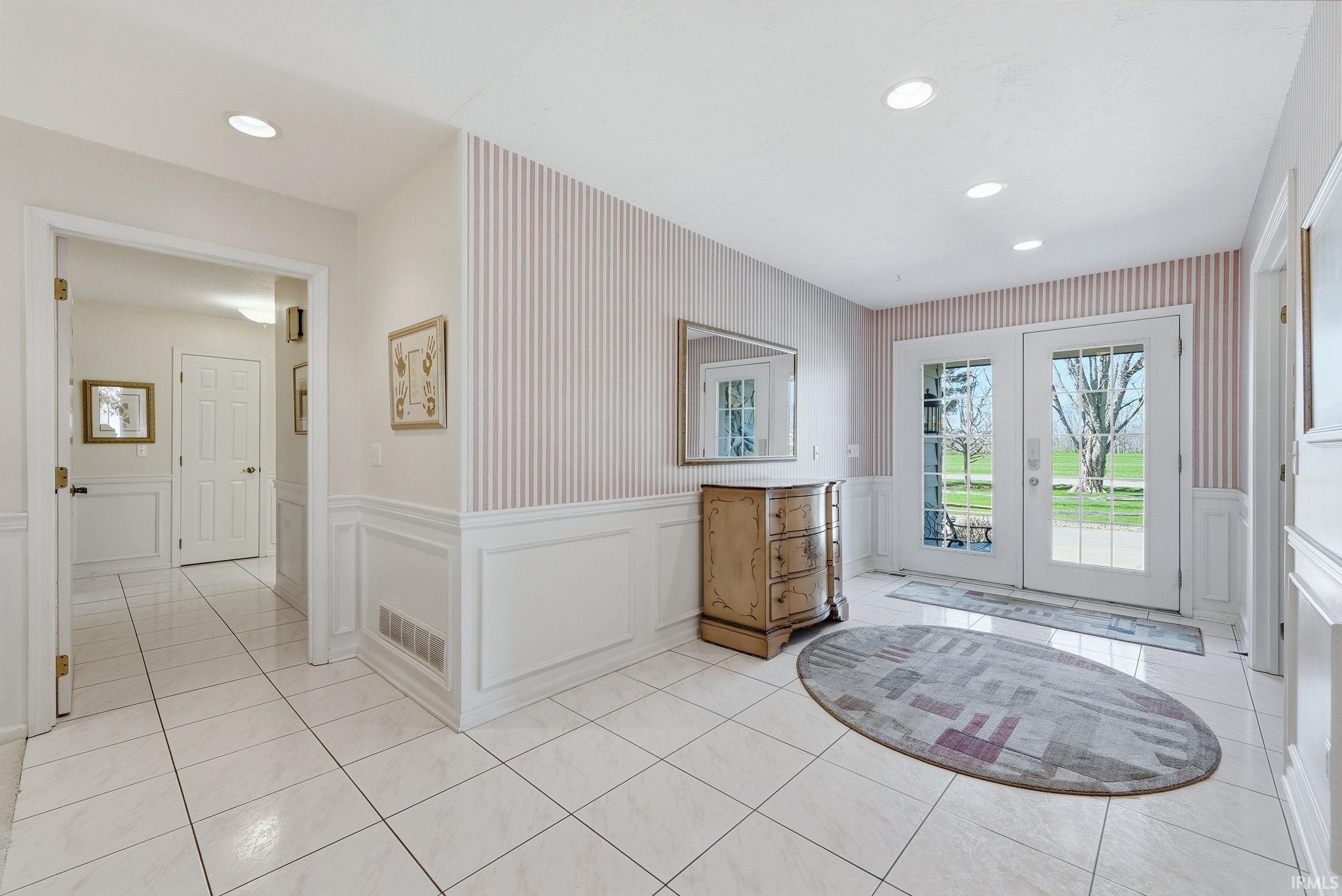 Entryway with a wainscoted wall, wallpapered walls, recessed lighting, a decorative wall, and french doors