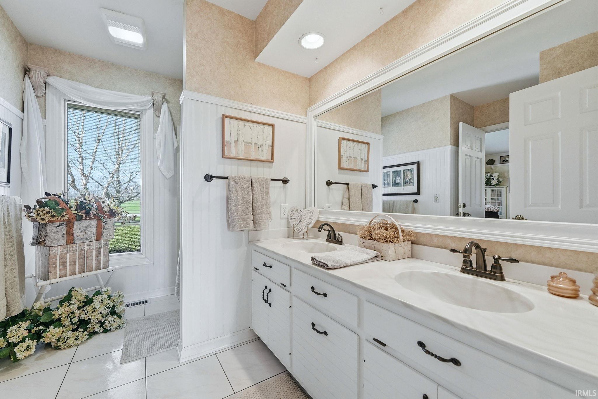 Bathroom with double vanity and light tile patterned floors