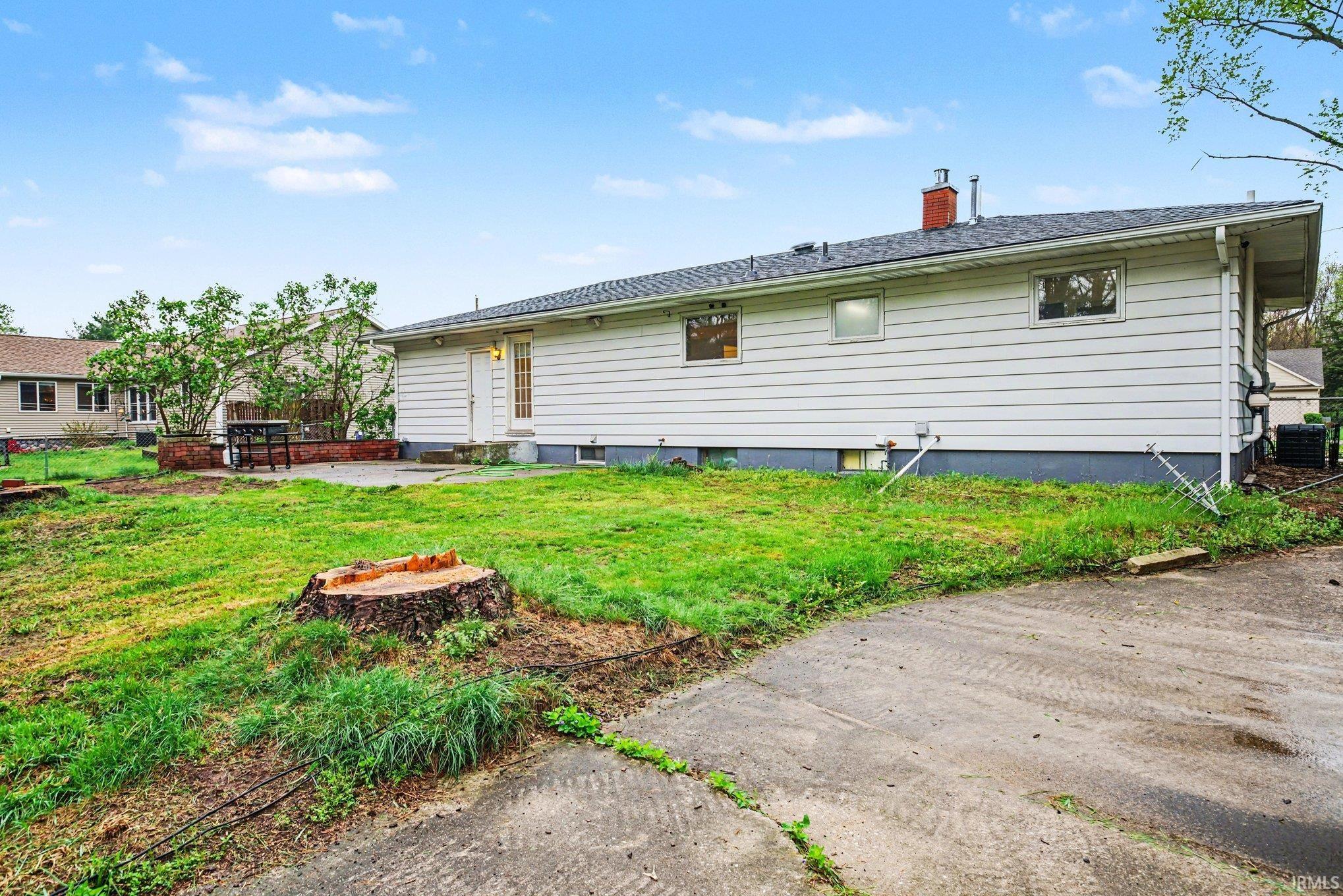 Rear view of house featuring a patio, a chimney, and an outdoor fire pit