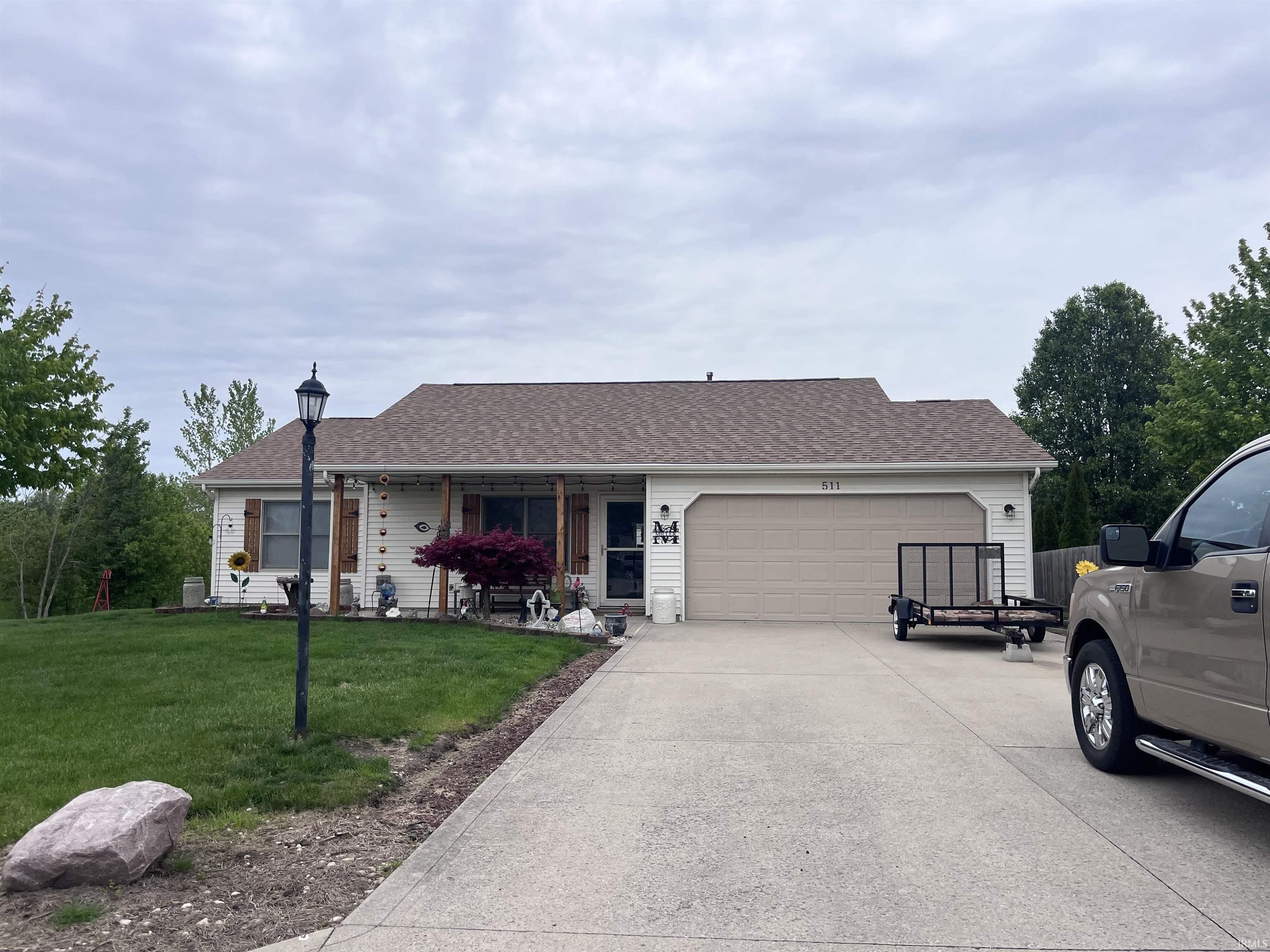 Ranch-style residence featuring a prominent two-car garage, concrete driveway, and covered front porch