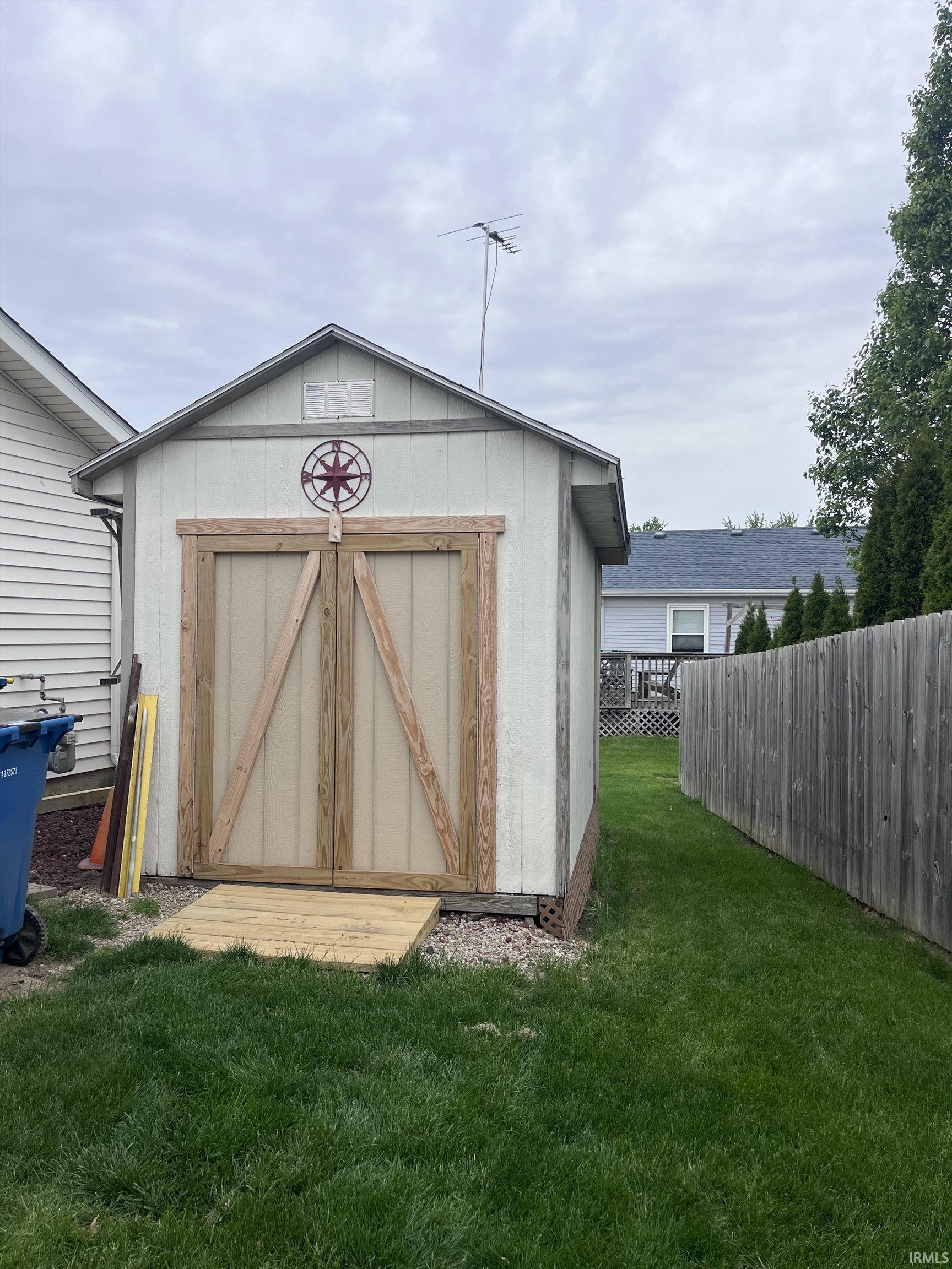 Outdoor storage shed with light-colored siding and a gable roof