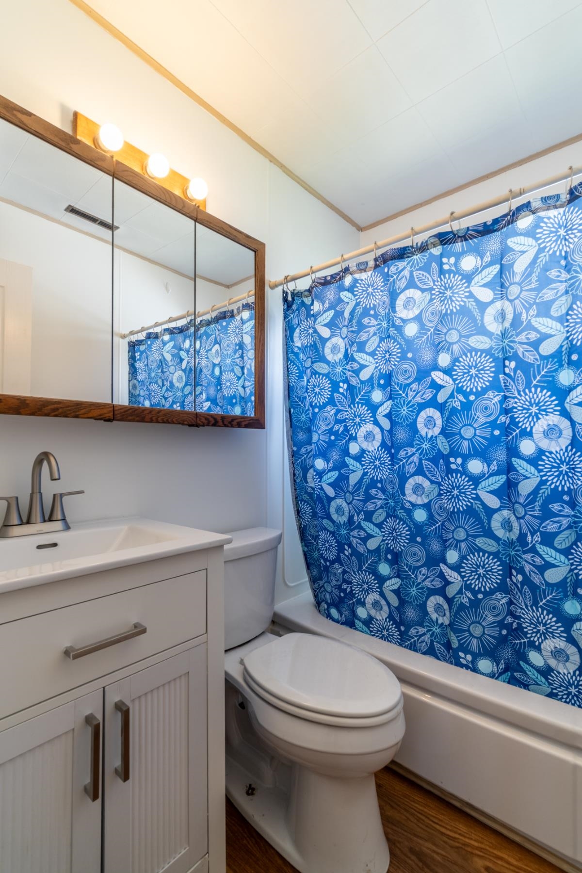 Bathroom featuring a white vanity with brushed nickel hardware, a white toilet, and a white bathtub