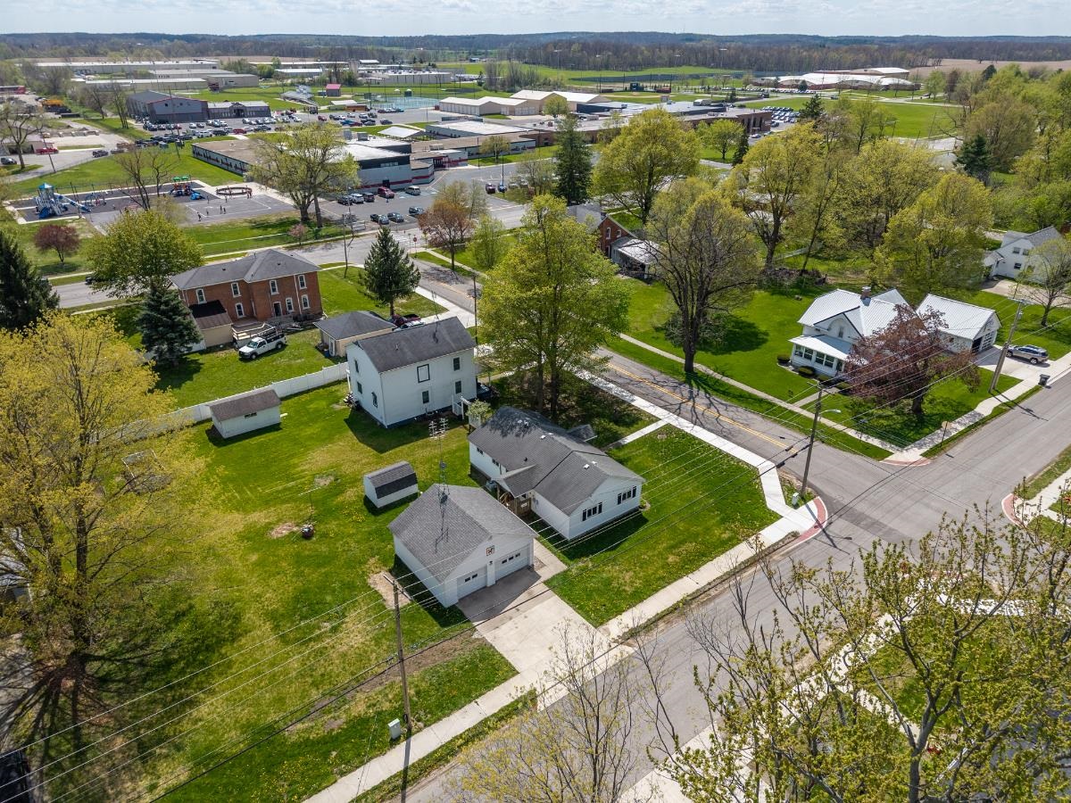 Expansive corner lot featuring a white two-story residence, a detached two-car garage, and a separate storage shed