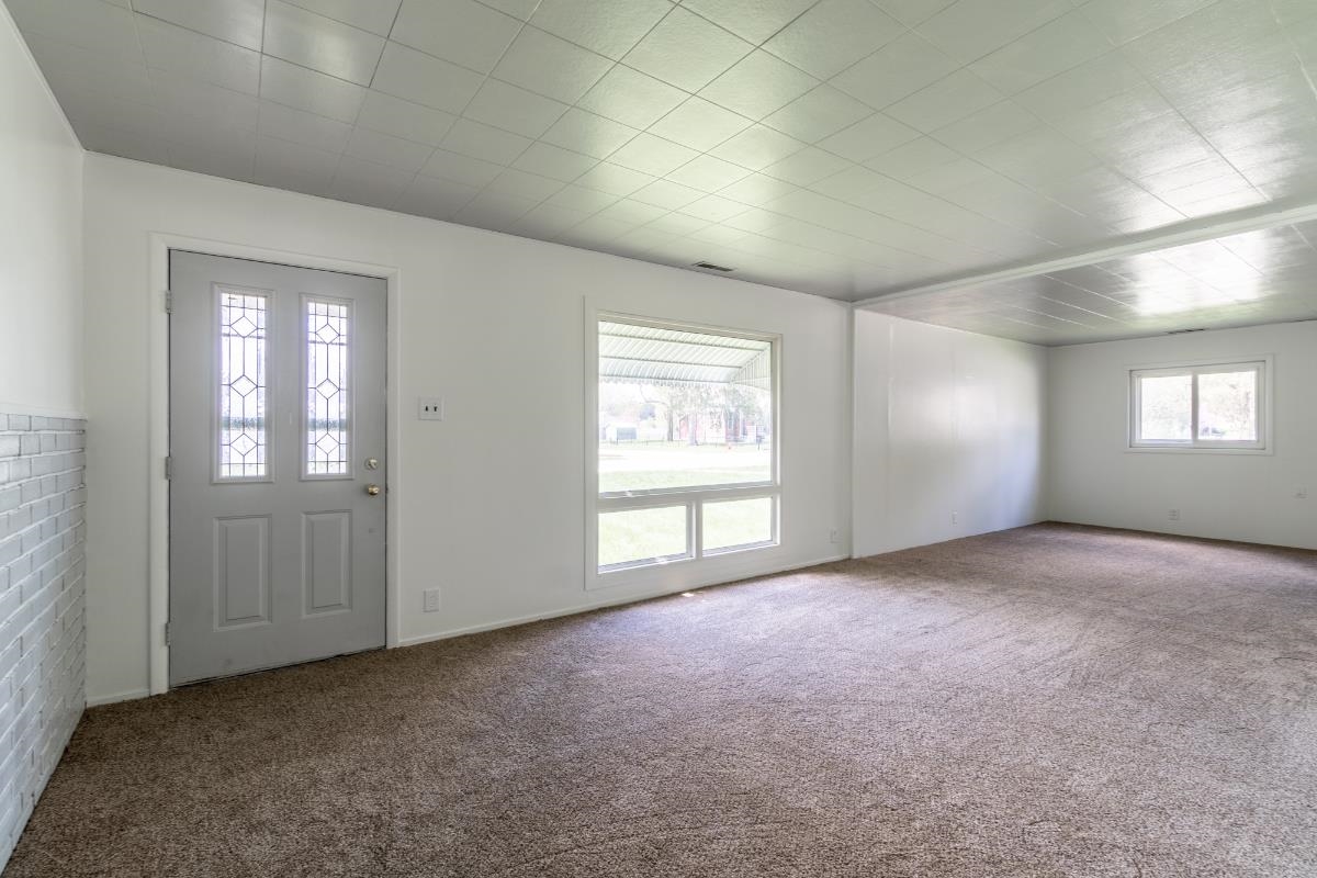 Entryway featuring a decorative glass panel door and a white brick-finish accent wall