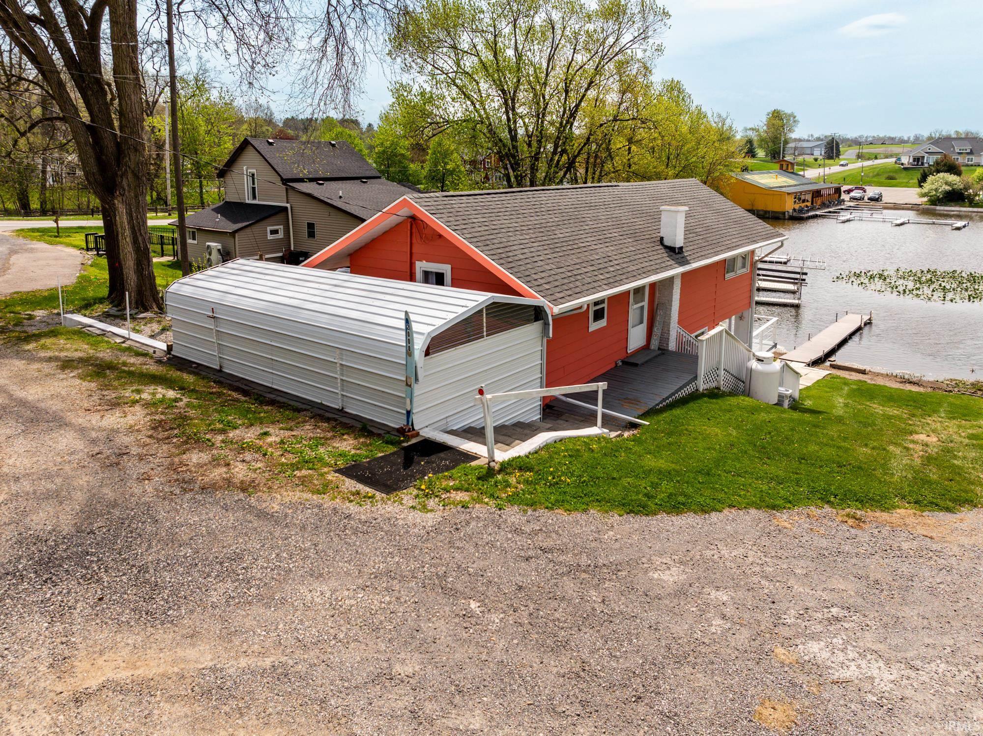Waterfront property featuring a red exterior, private dock, and a metal storage structure