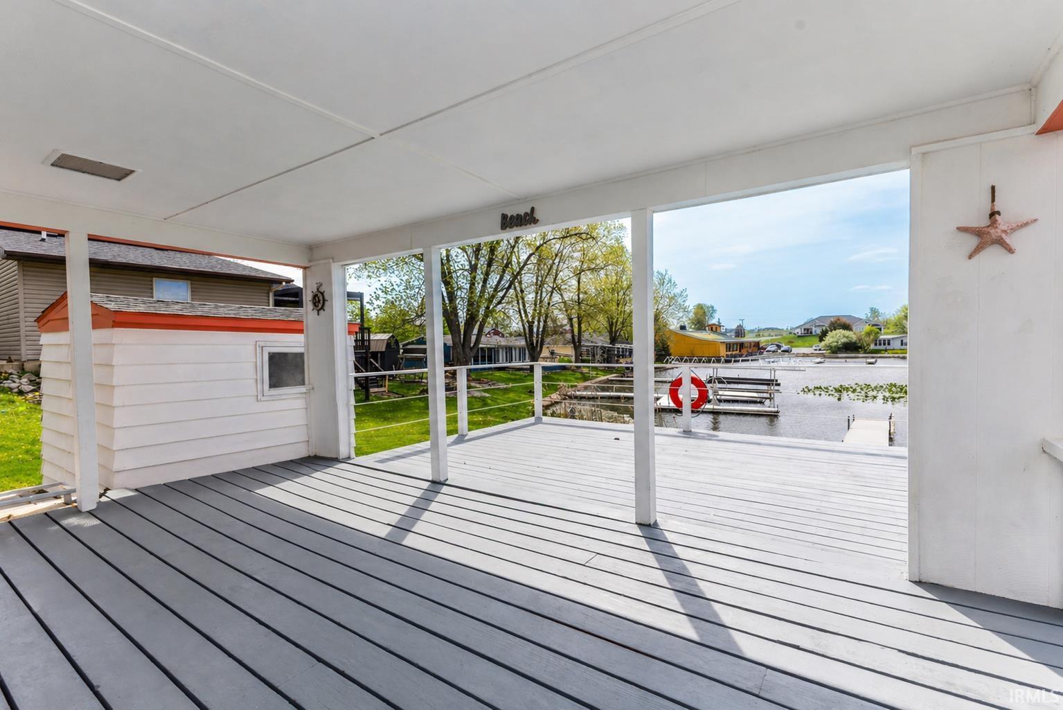 Covered porch with composite decking, overlooking a private dock and a body of water
