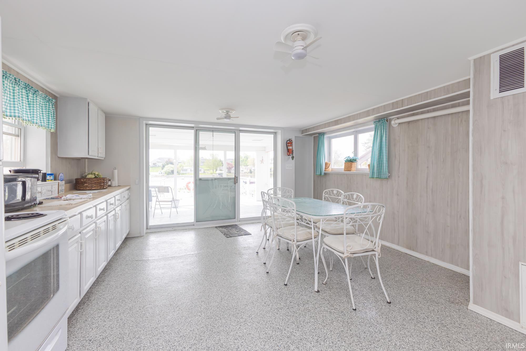 Kitchen and dining area featuring speckled flooring, white cabinetry, and sliding glass doors leading to an exterior space