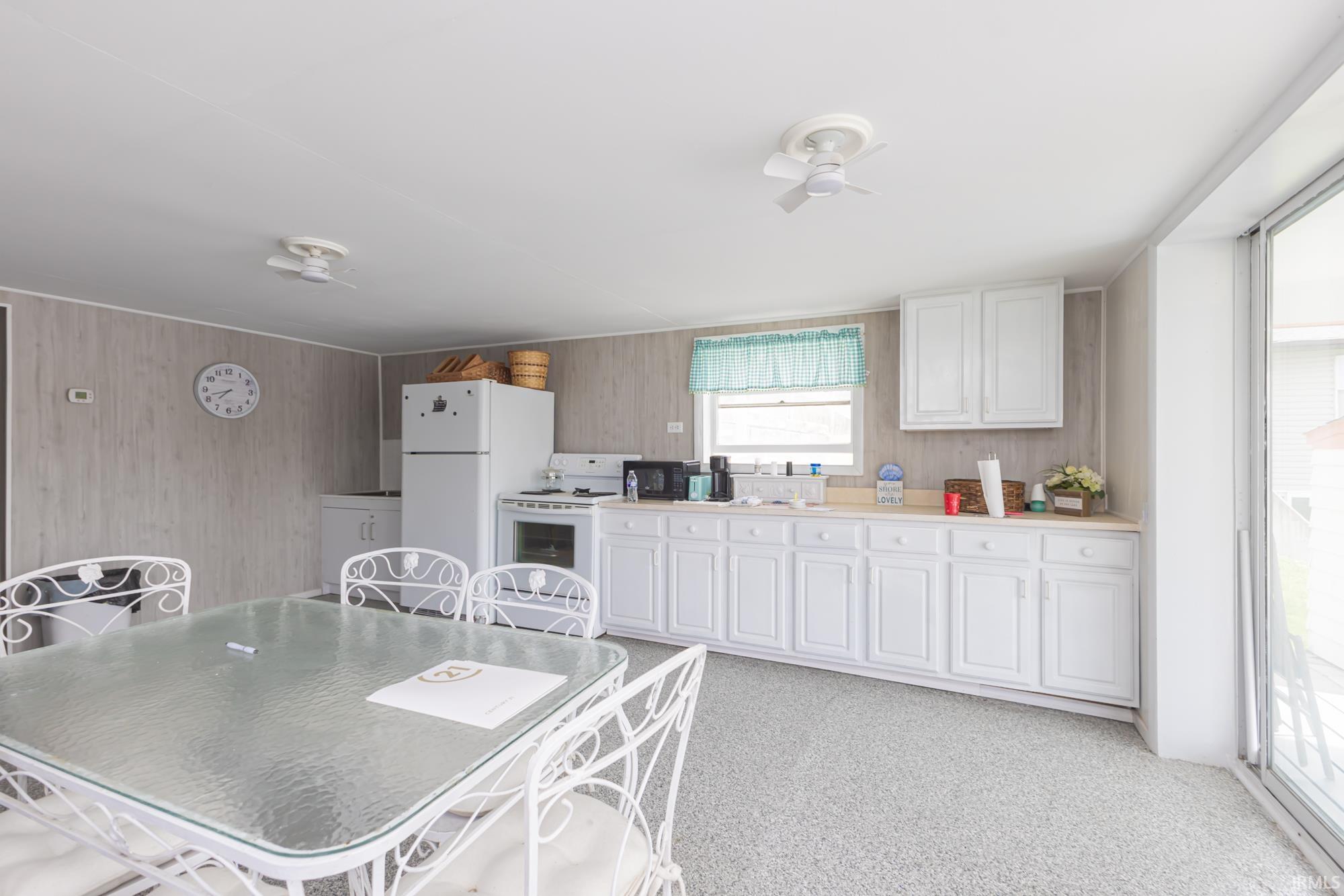 Kitchen area with white cabinetry, light countertops, and a full suite of white appliances