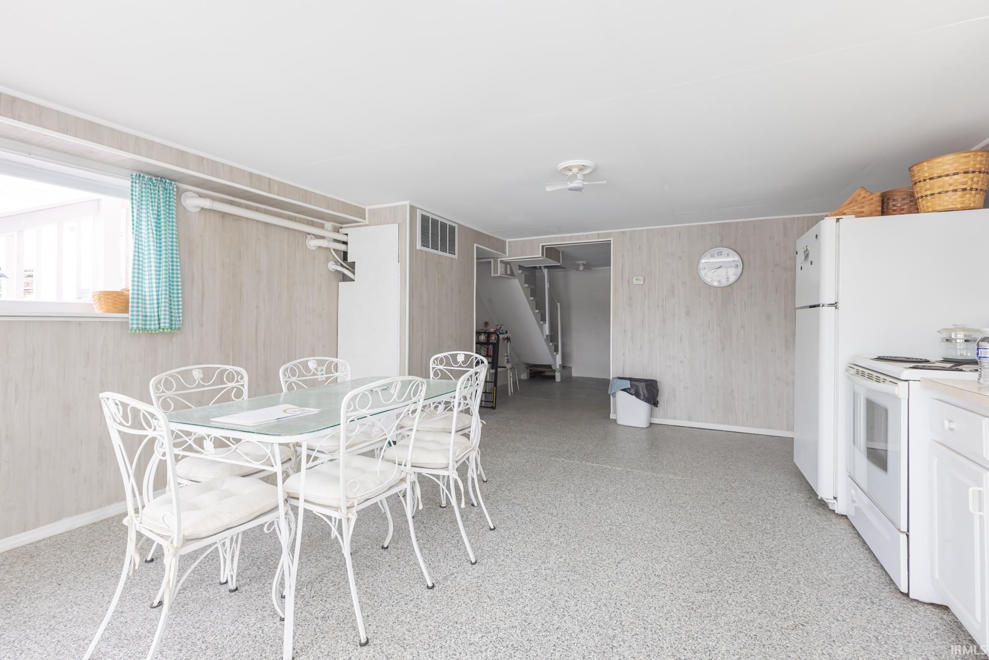 Eat-in kitchen featuring white appliances, light-toned wall paneling, and a light speckled flooring