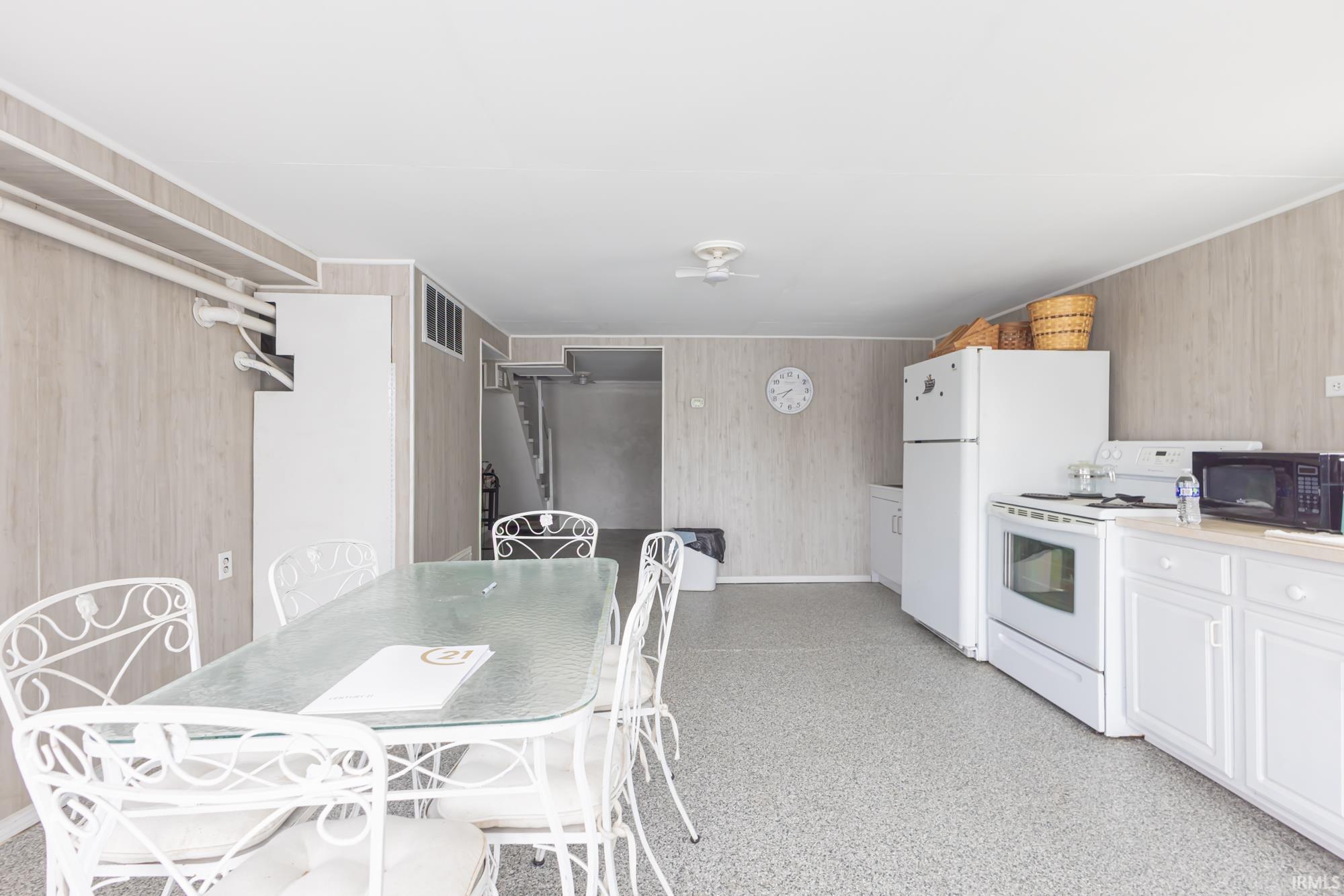 Open-concept kitchen and dining area featuring white appliances, white cabinetry, and light gray paneled walls