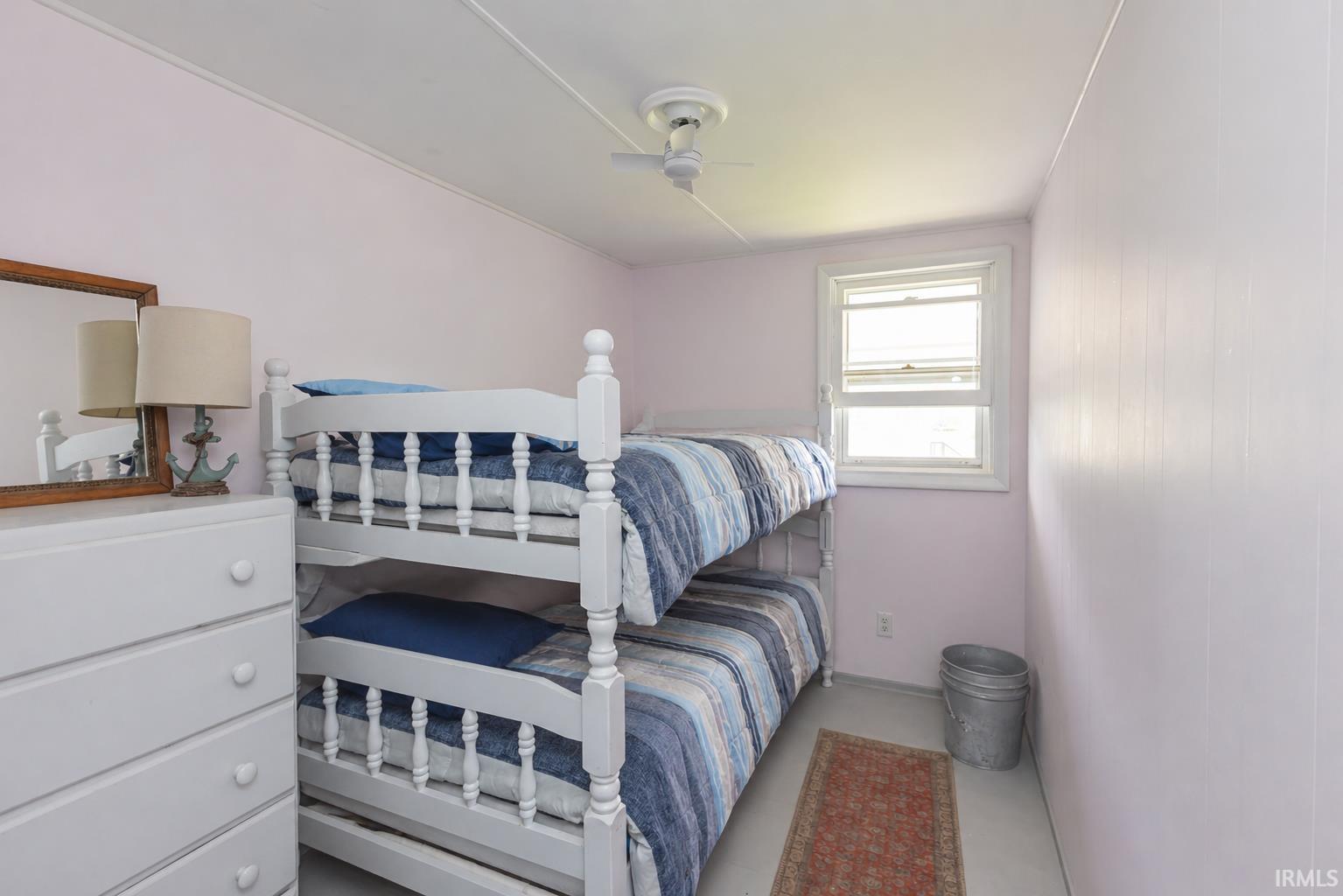 Room featuring light pink walls, a white-framed window, and a white ceiling fan