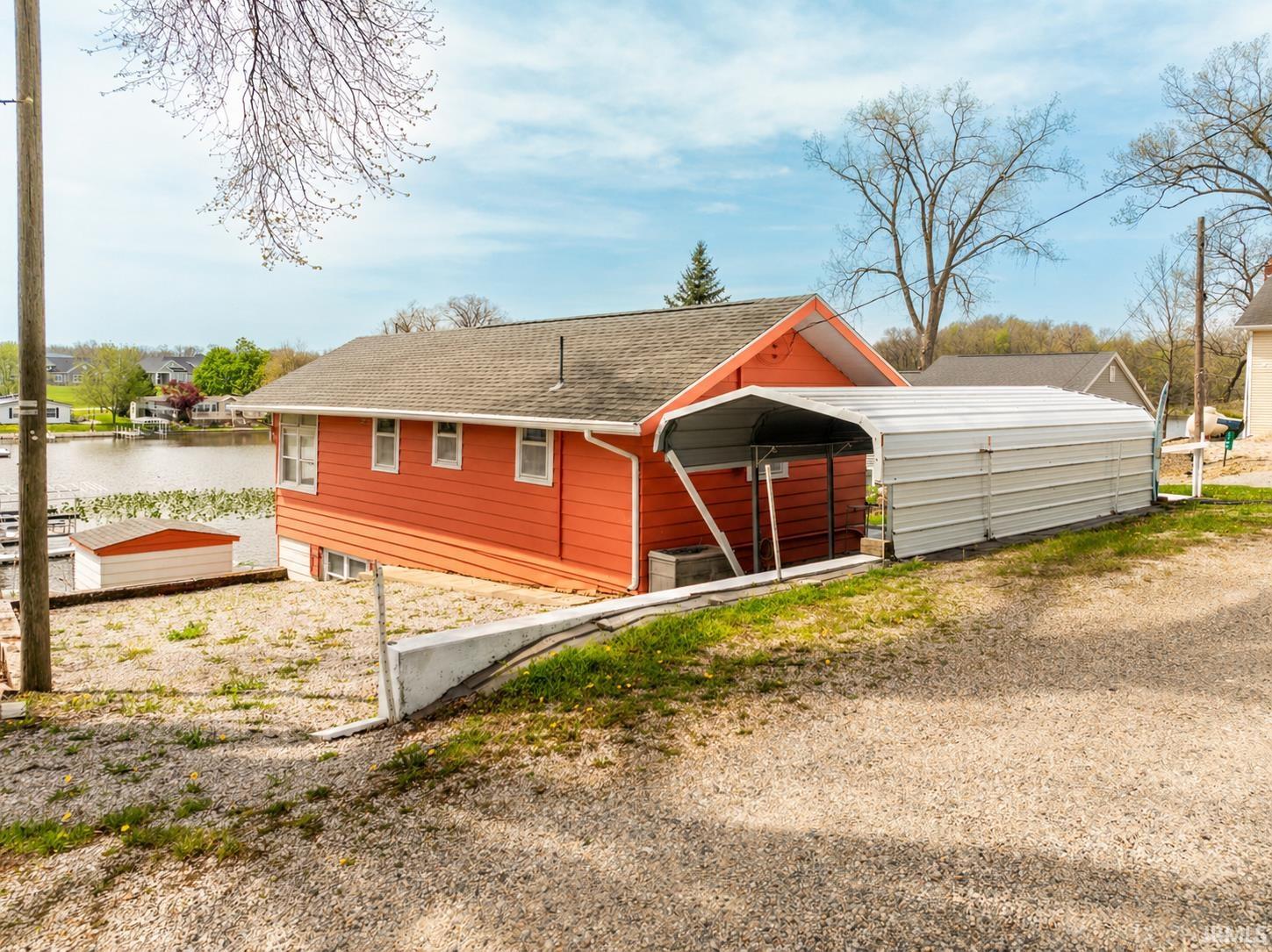 Red-sided structure with a gray shingle roof, offering waterfront access with a dock