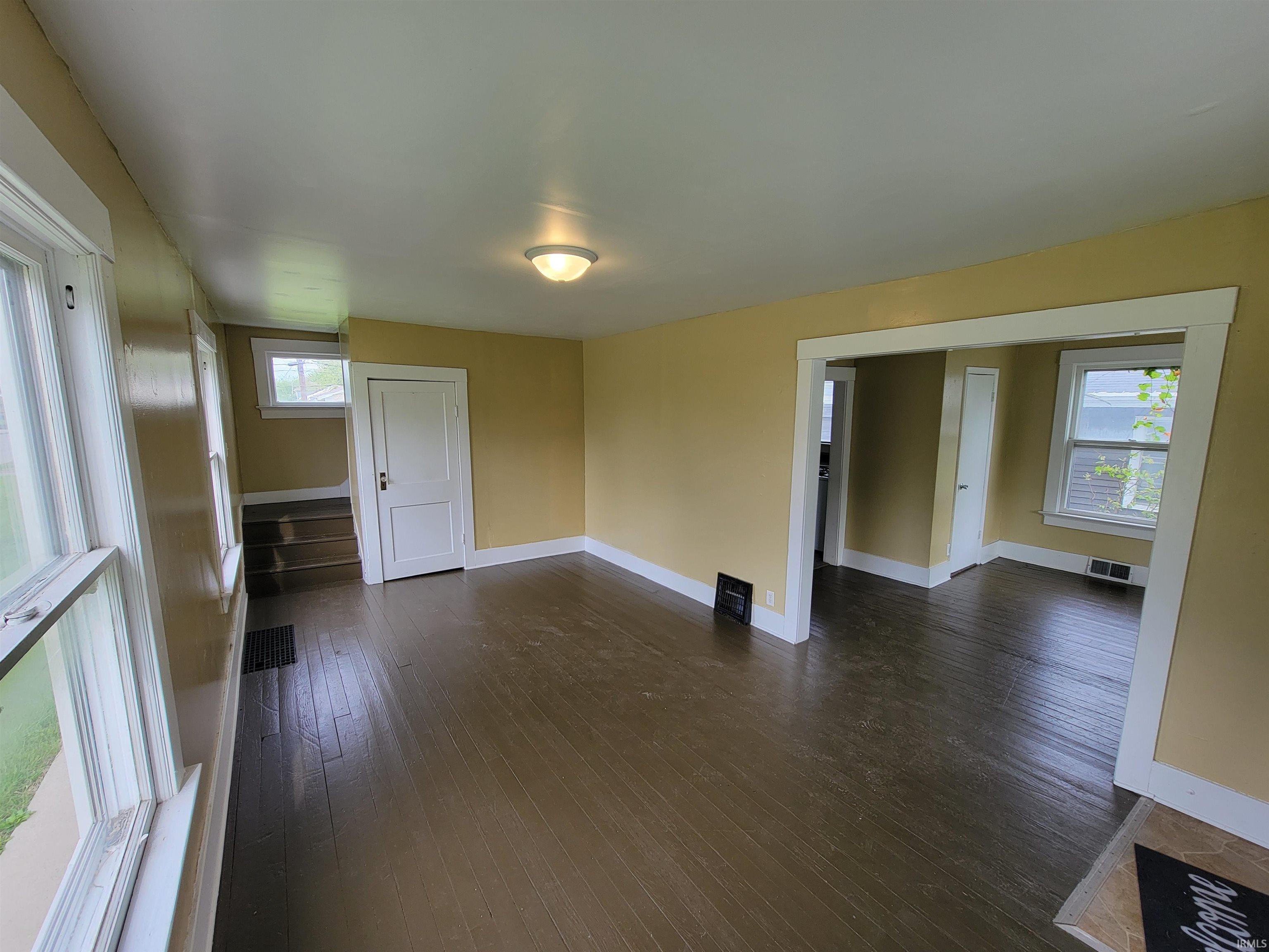 Open concept living space featuring dark wood-finish flooring, light yellow wall color, white trim, and a flush mount ceiling light