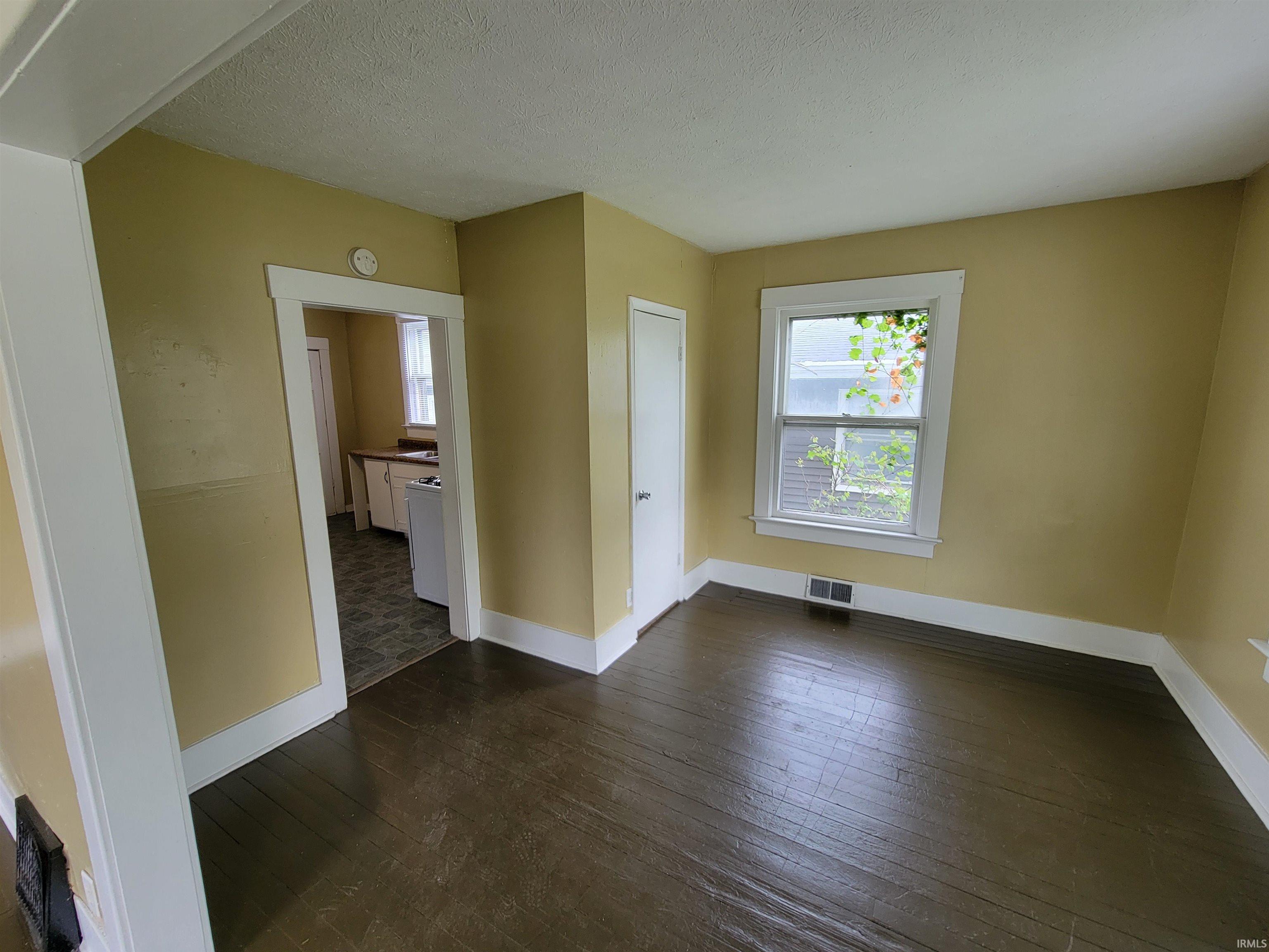 Room with dark wood-finish flooring and light yellow walls