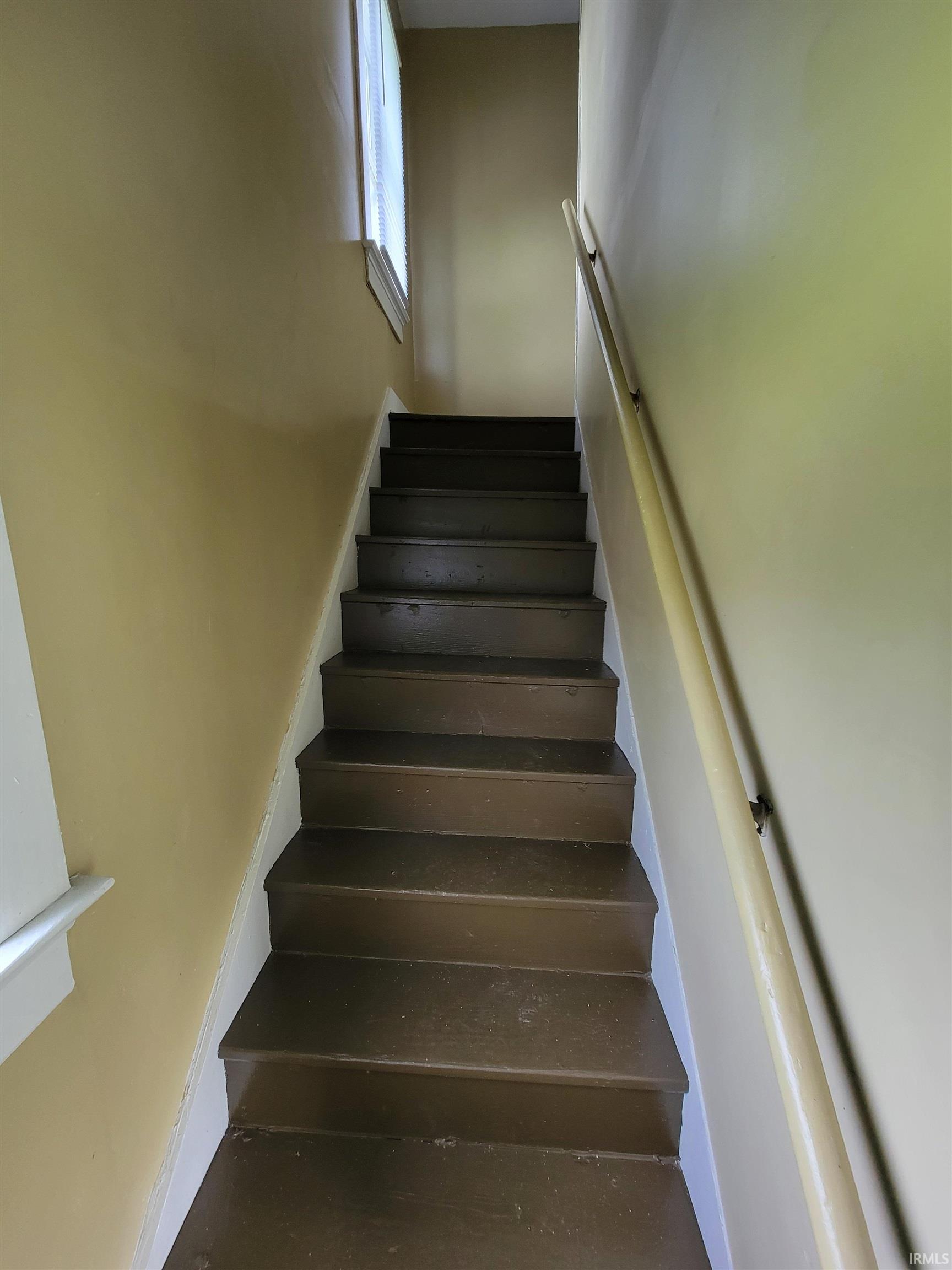 Interior staircase featuring wood treads, a light-toned handrail, and a window providing natural illumination