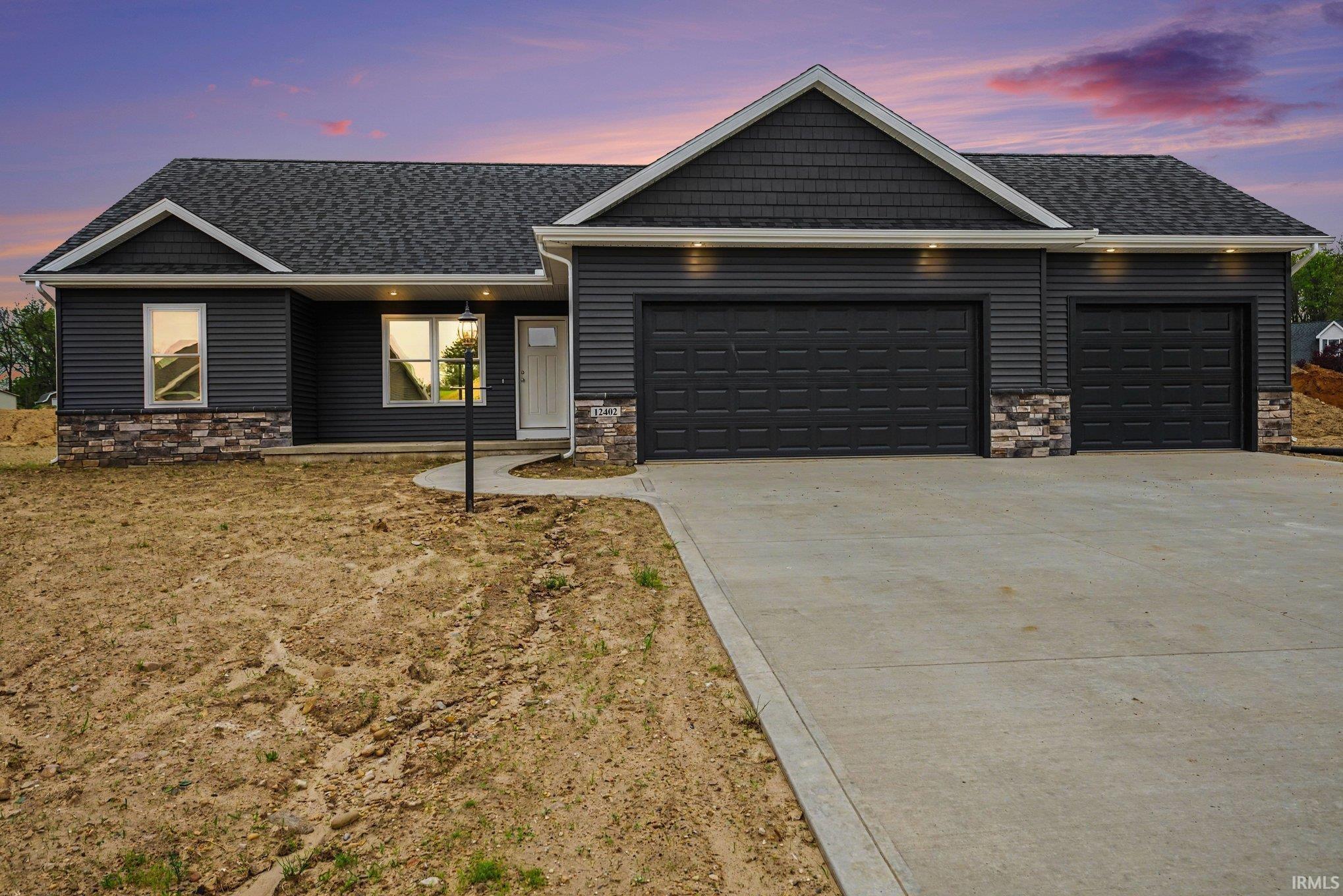 Ranch-style exterior featuring dark gray horizontal siding and decorative stone accents