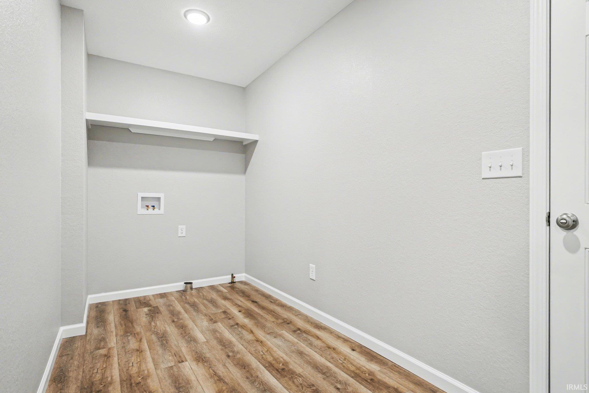 Dedicated utility space featuring wood-finish flooring, light gray walls, and a recessed ceiling light