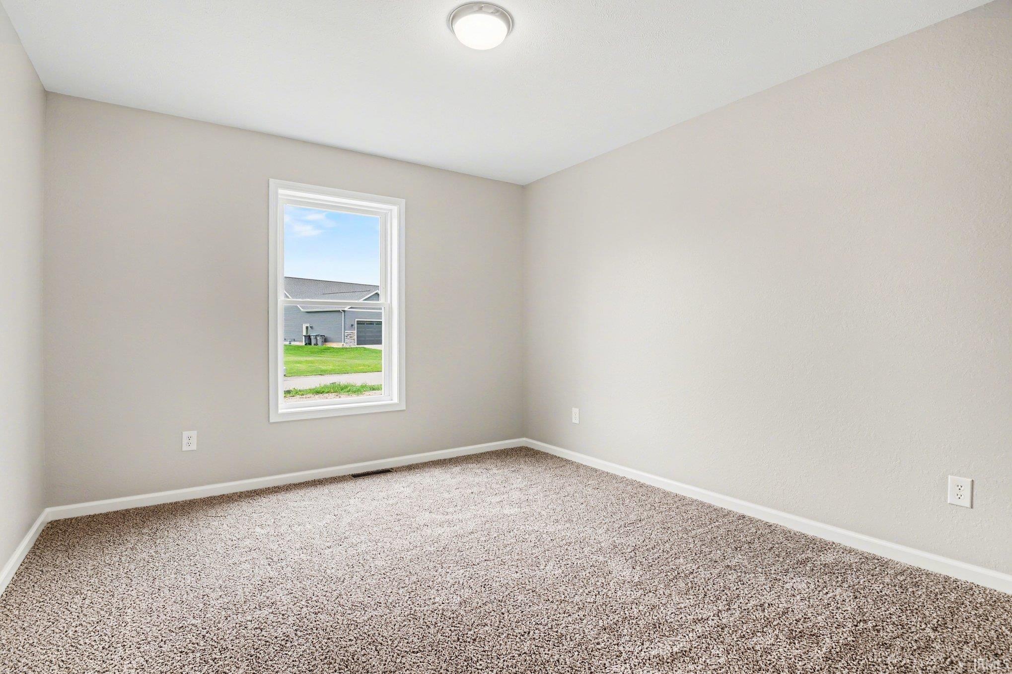 Bright room featuring neutral-toned walls, plush carpet flooring, a single pane window, and a flush mount ceiling light fixture