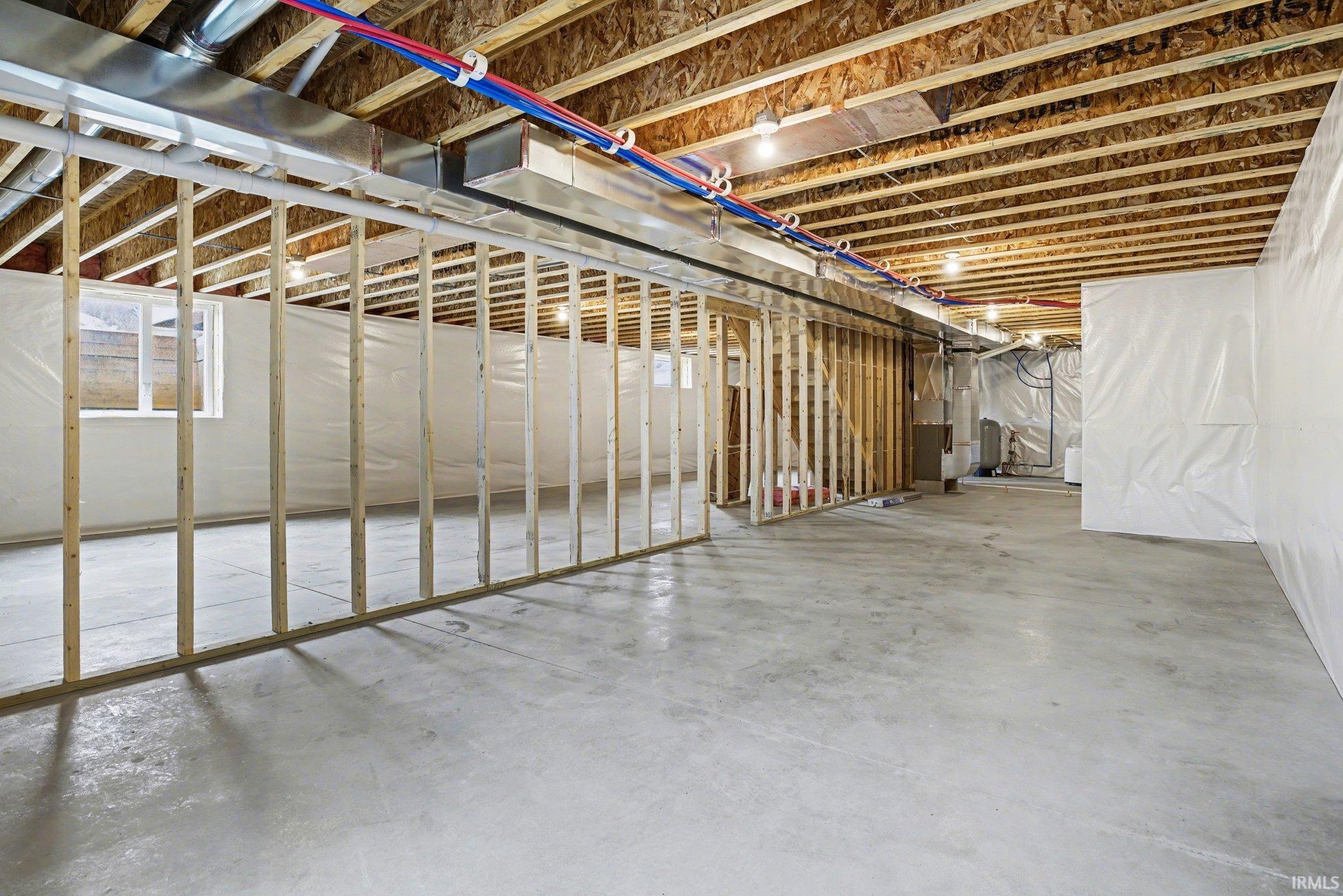 Unfinished basement with concrete flooring and exposed wooden ceiling joists