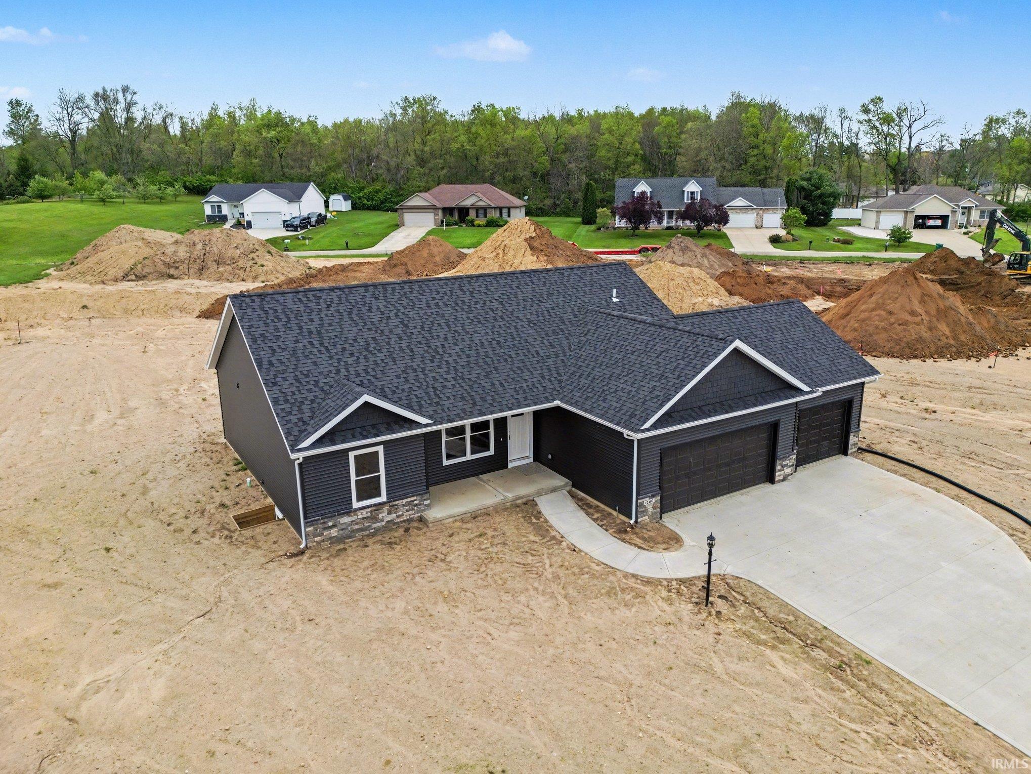 Newly constructed residence featuring dark siding, a light stone veneer accent, and a dark asphalt shingle roof