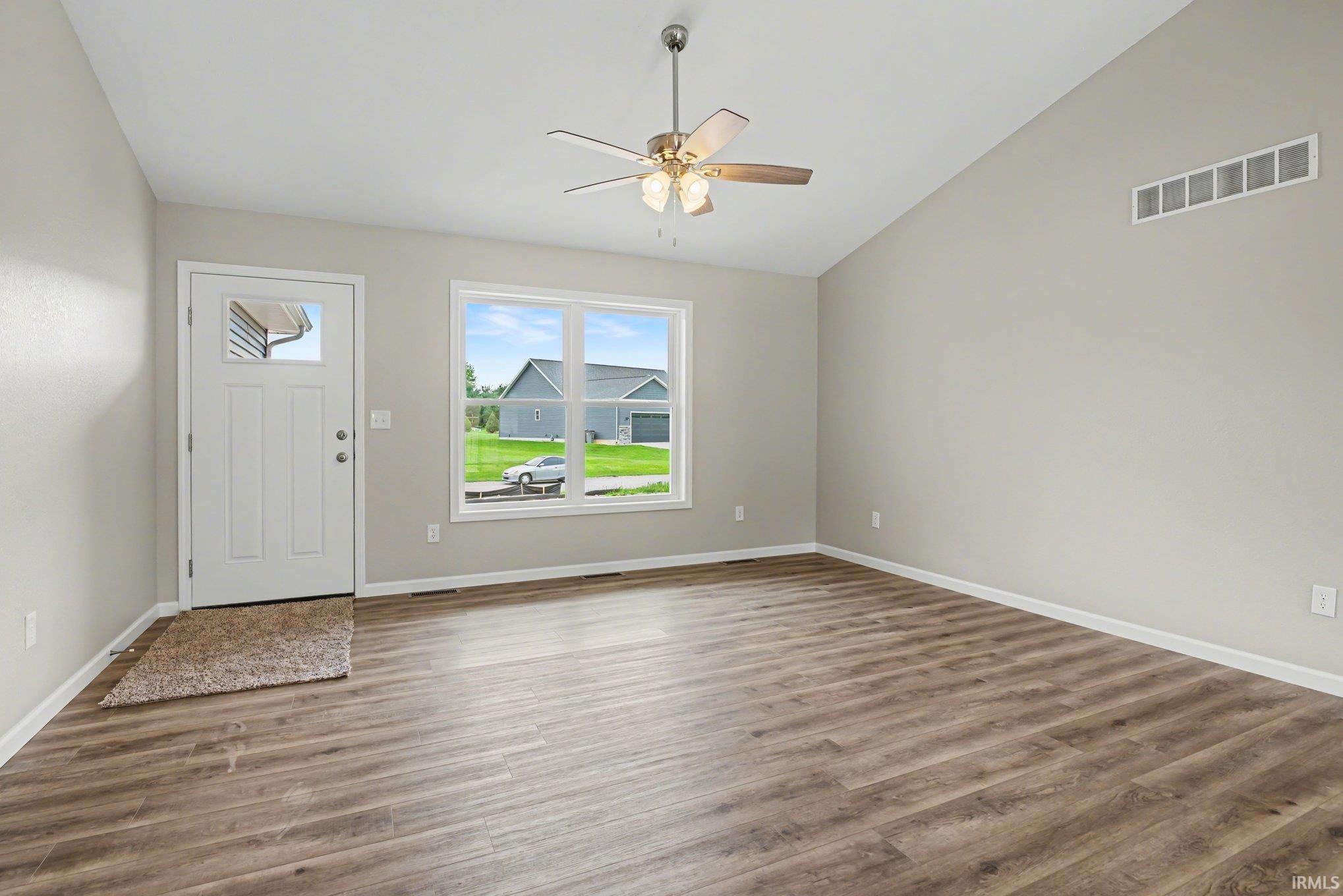 Spacious room featuring vaulted ceilings, wood-finish flooring, and a contemporary ceiling fan with integrated lighting