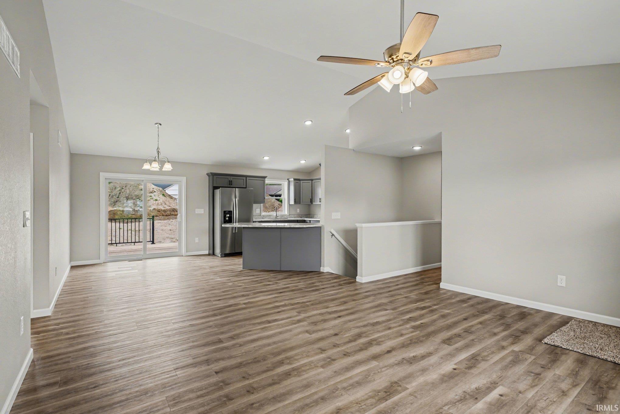 Open-concept living area featuring wood-finish flooring, vaulted ceilings, and recessed lighting