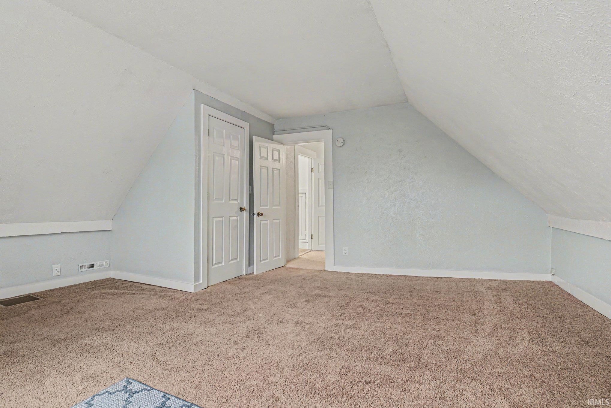 Carpeted room featuring a sloped ceiling, light blue walls, and white trim