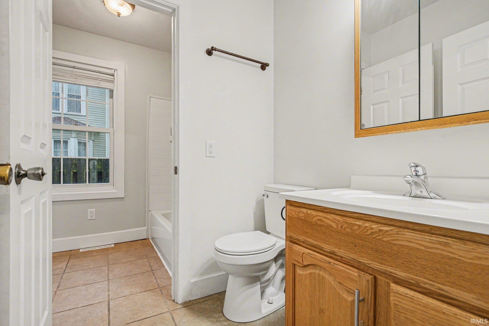 Bathroom featuring a wood-finish vanity with a white countertop, an integrated sink, and a chrome faucet