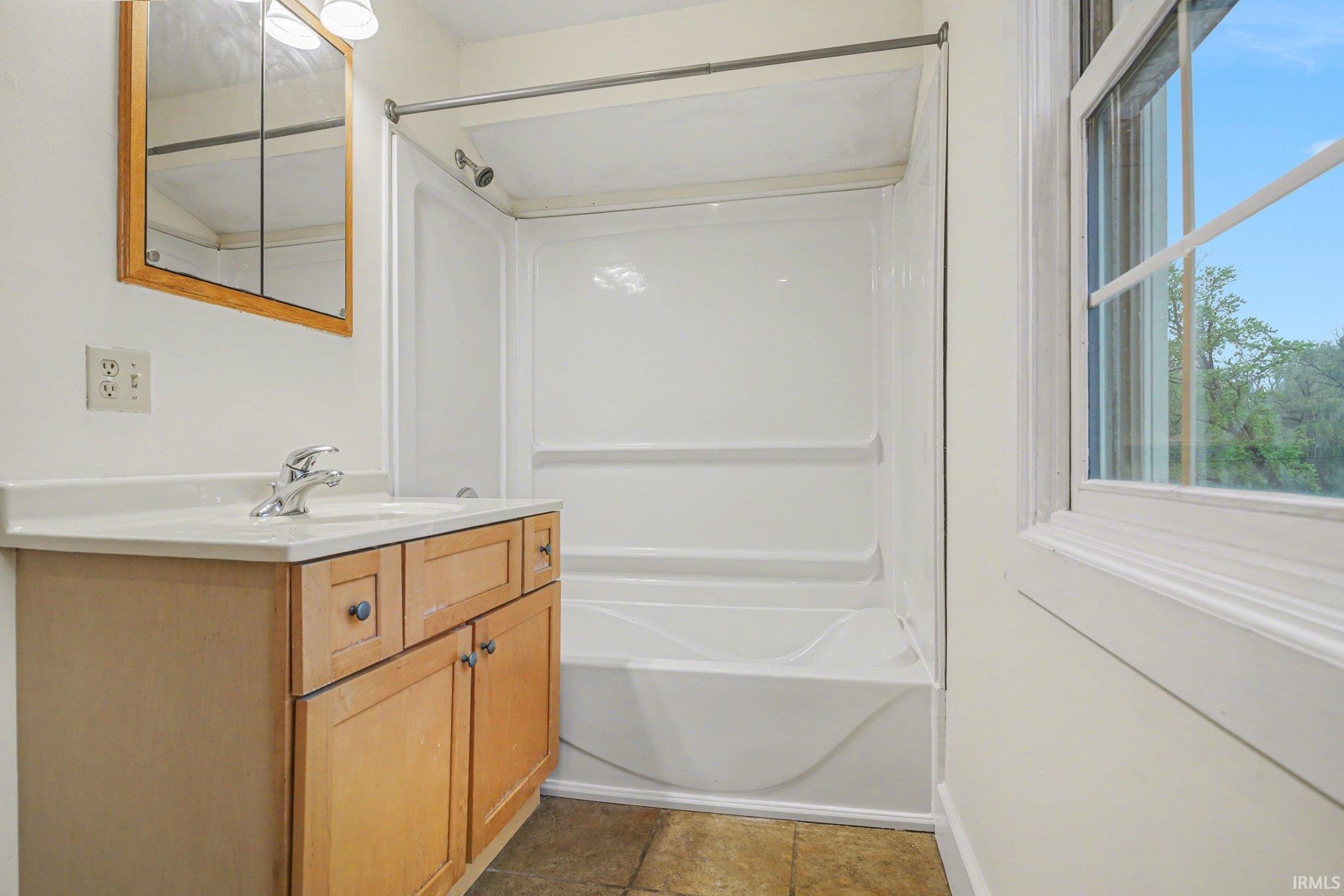 Bathroom featuring a wood-tone vanity with a light countertop, integrated sink, and chrome faucet