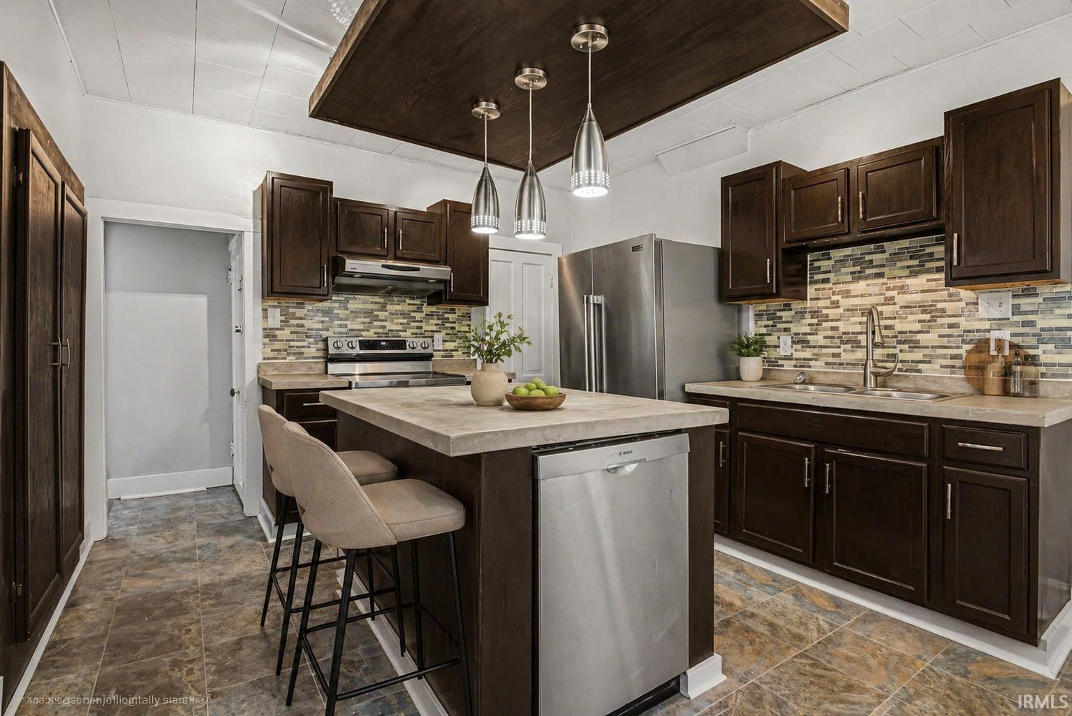Kitchen featuring dark wood-finish cabinetry, stainless steel appliances, and a tiled backsplash