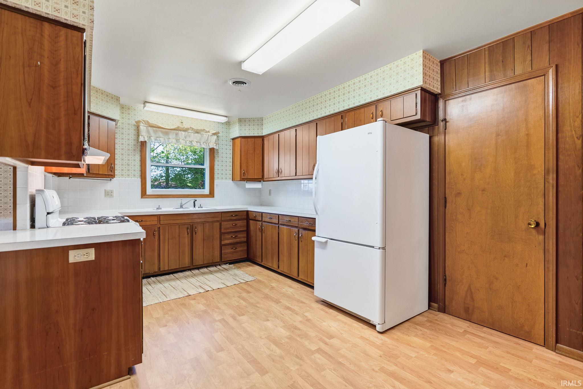 Kitchen featuring wood-finish cabinetry, white countertops, and wood-finish flooring